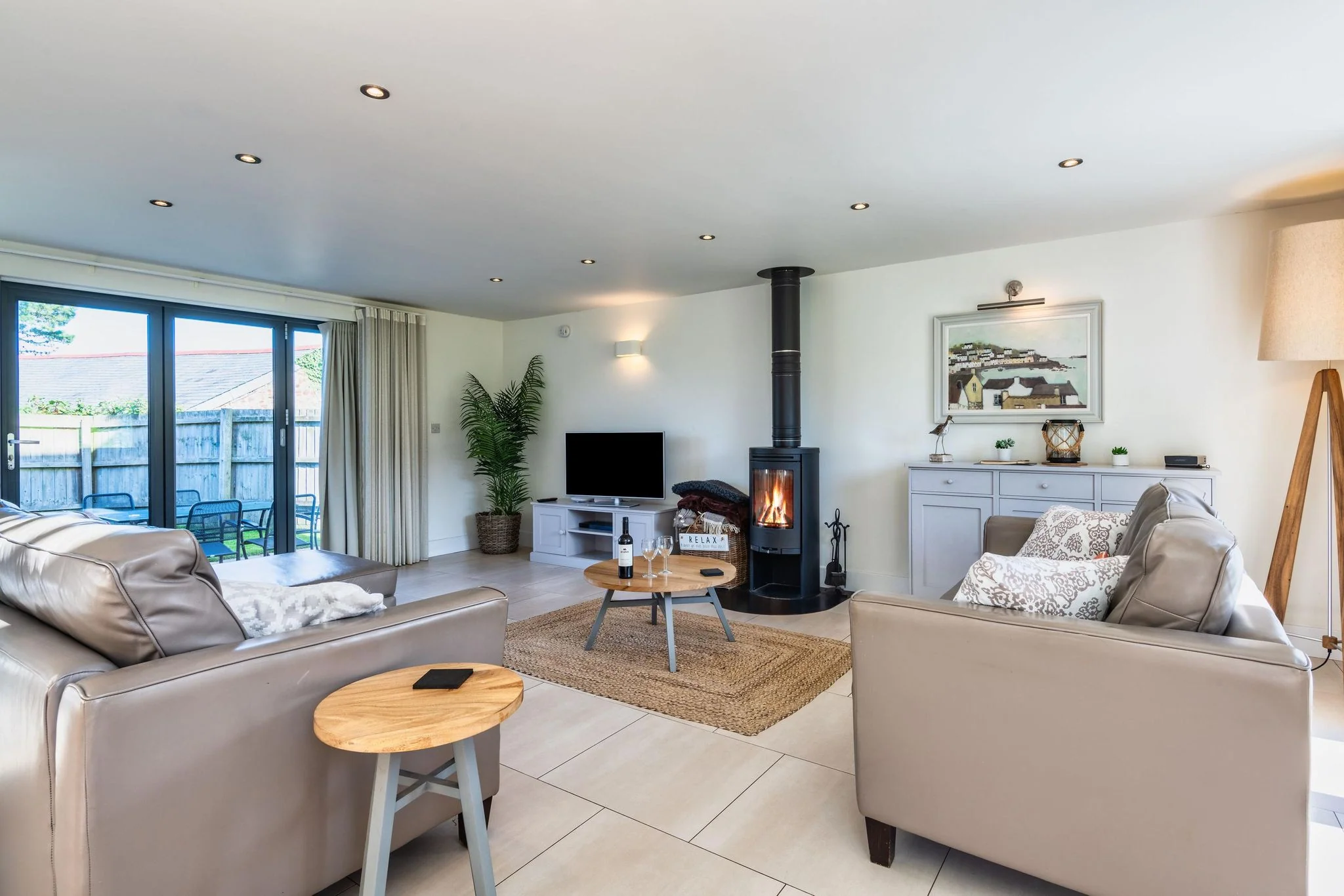 Arundell open-plan living and dining area with a wood-burning stove and garden bifold doors