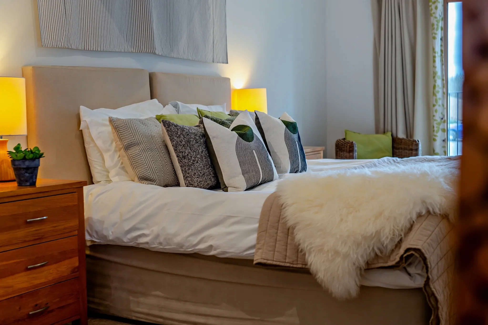 Barley Park double bedroom close-up of the upholstered headboard with layered scatter cushions and matching bedside lamps.