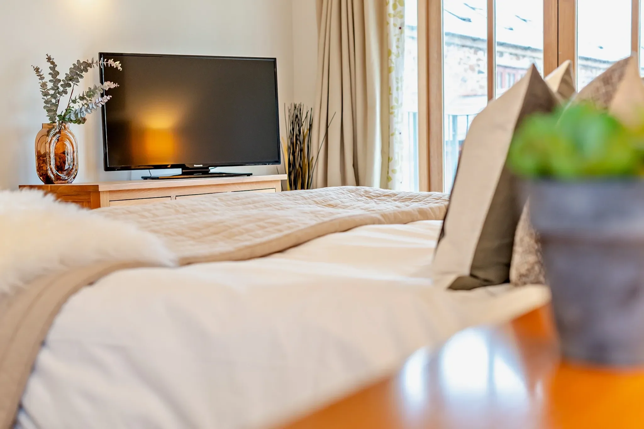 Barley Park double bedroom with a neatly made bed, TV on a light wood unit and french doors letting in natural light.
