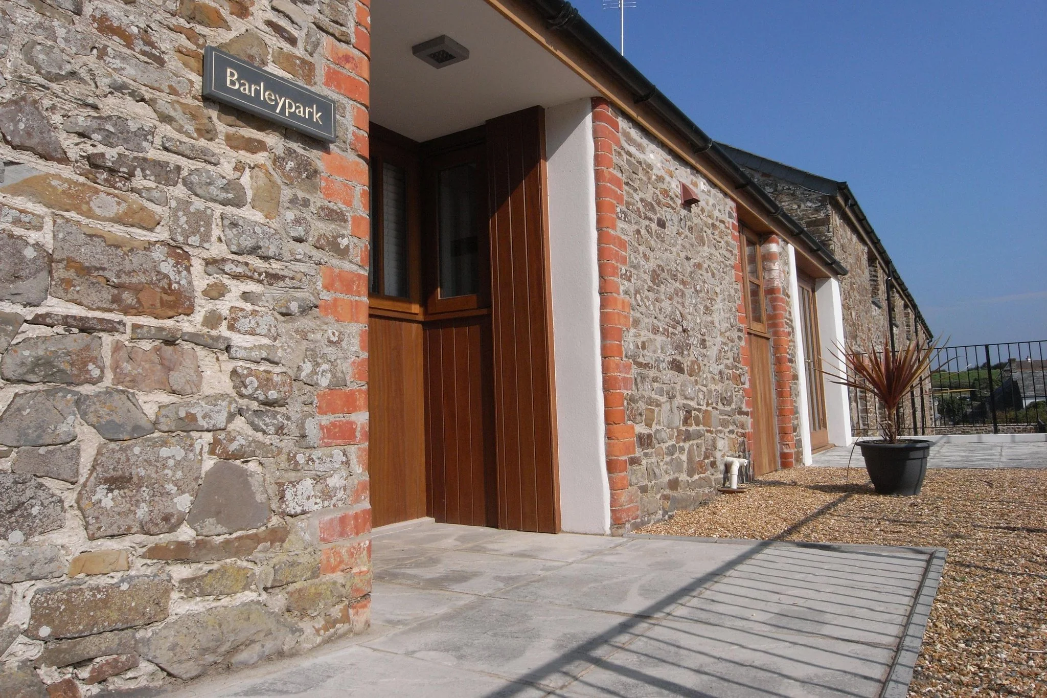 Barley Park entrance door set into a traditional Cornish stone wall with a named slate sign above the wooden front door.