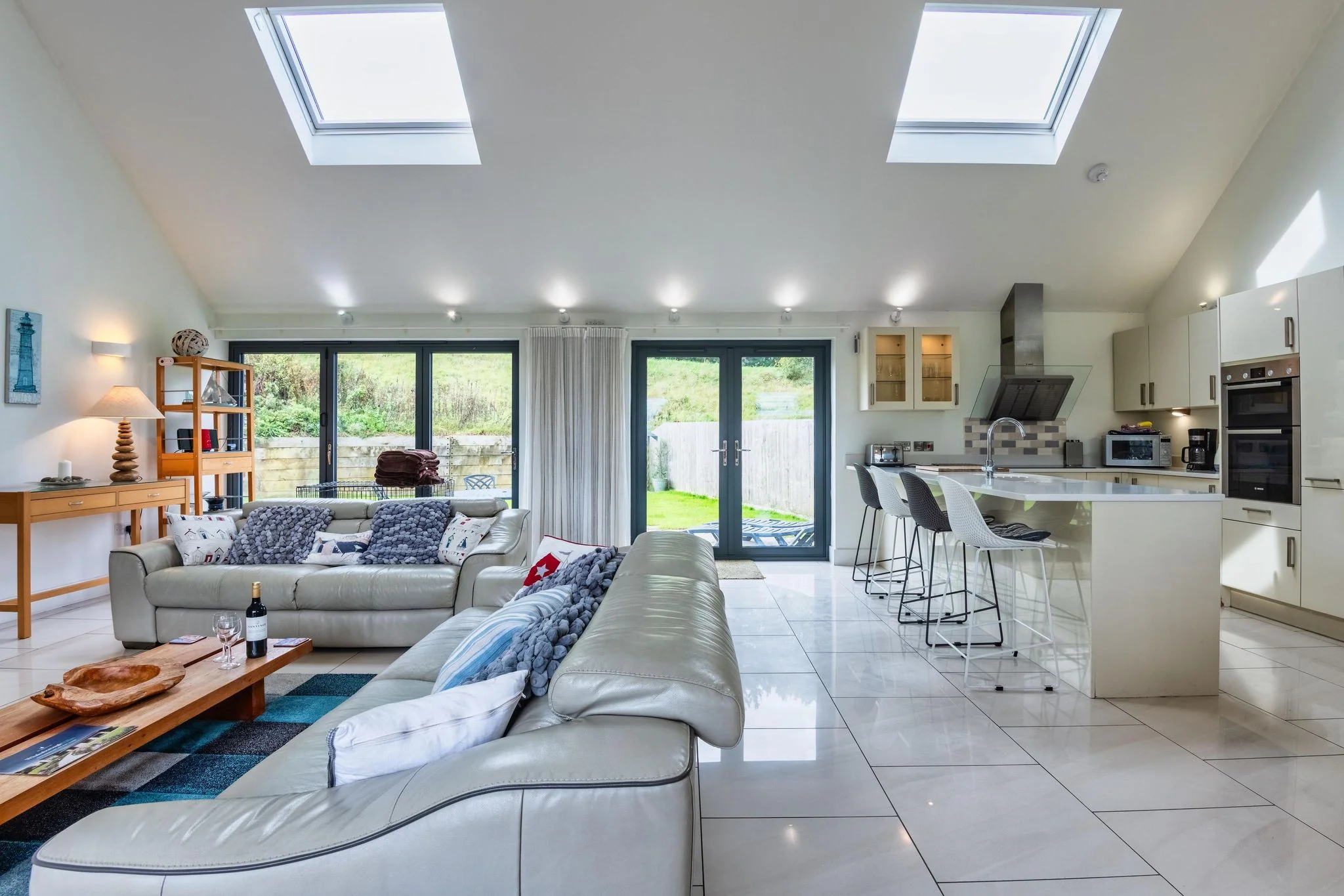 Open-plan living and kitchen at Beachcombers, looking out through full-height garden doors