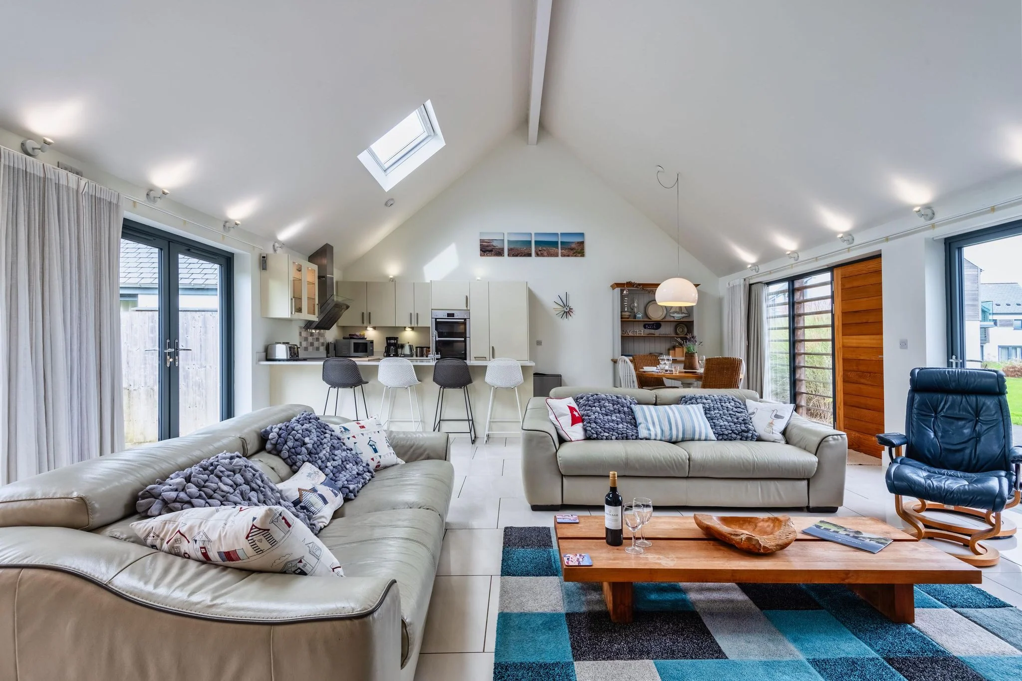 Beachcombers open-plan living space with a vaulted ceiling, roof lights, sofas and the kitchen beyond