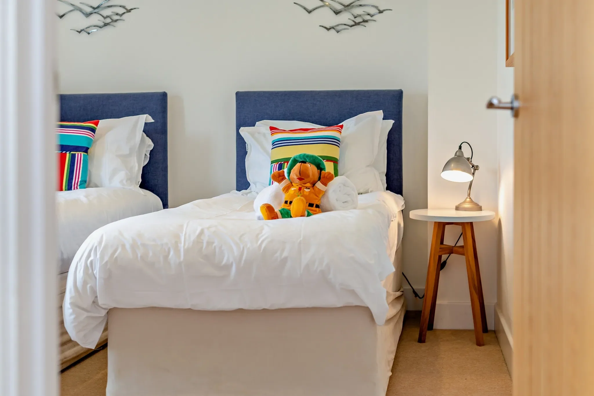 Eagles Nest twin bedroom close-up of the navy-headboard single beds with striped pillows and seagull wall art above.