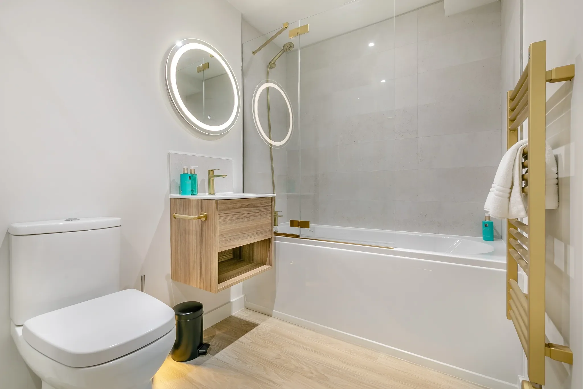Gwari Spa Barn bathroom with full-size bath, overhead shower, twin illuminated round mirrors and gold heated towel rail.