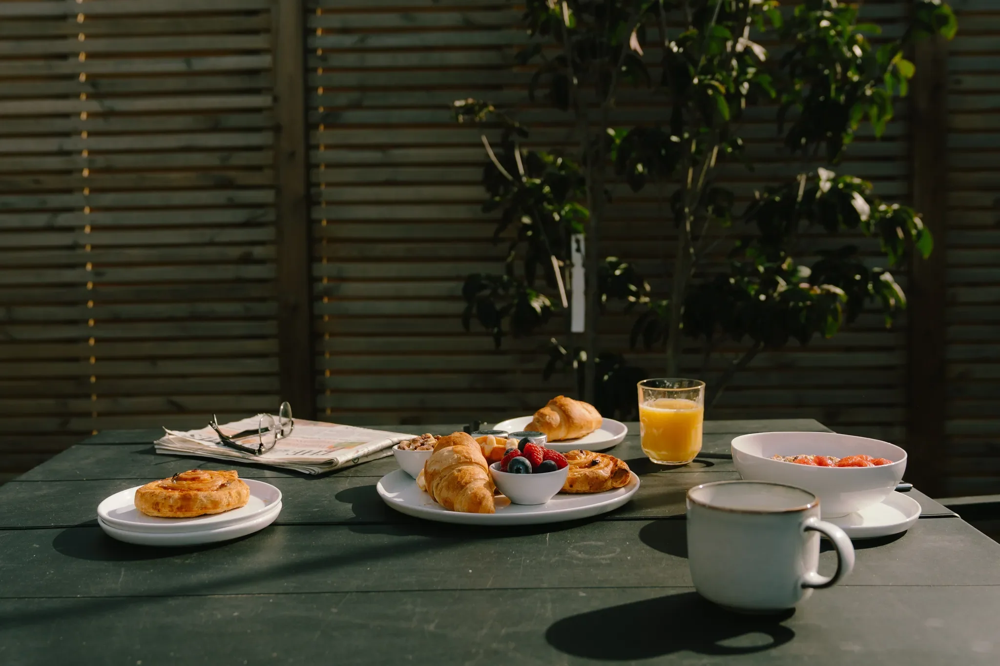 Gwari Spa Barn outdoor dining table close up with a morning spread of croissants, pastries, fruit and orange juice.