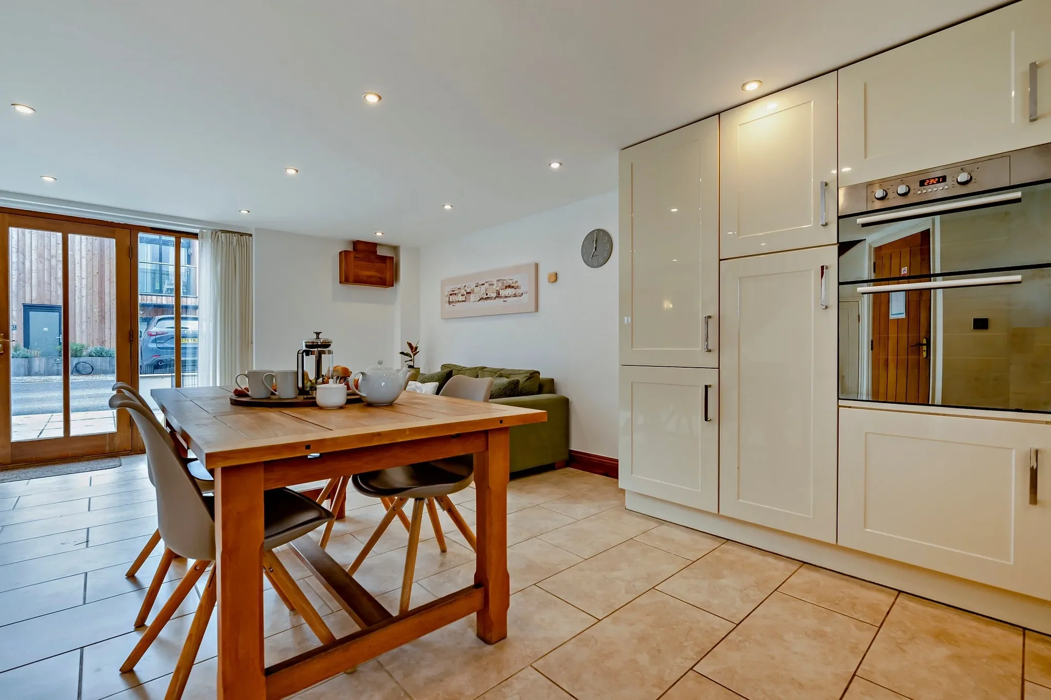 Jack's House dining area with solid oak table set for breakfast, built-in double ovens and patio doors filling the room with light.