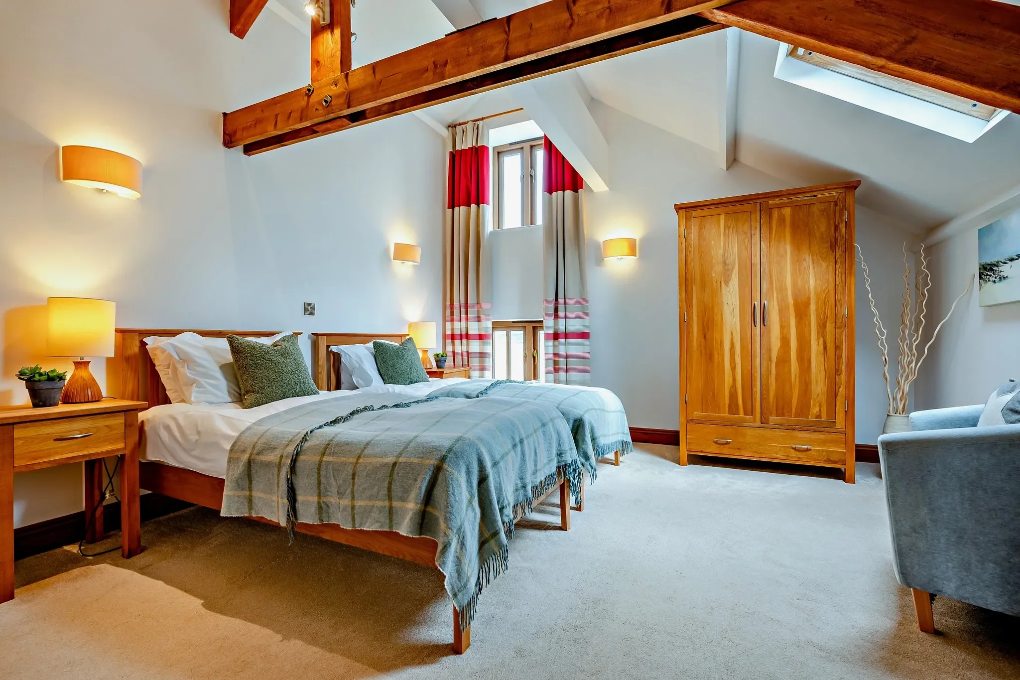 Jack's House master bedroom with vaulted ceiling, exposed beams, king-size bed dressed in teal and a roomy oak wardrobe.