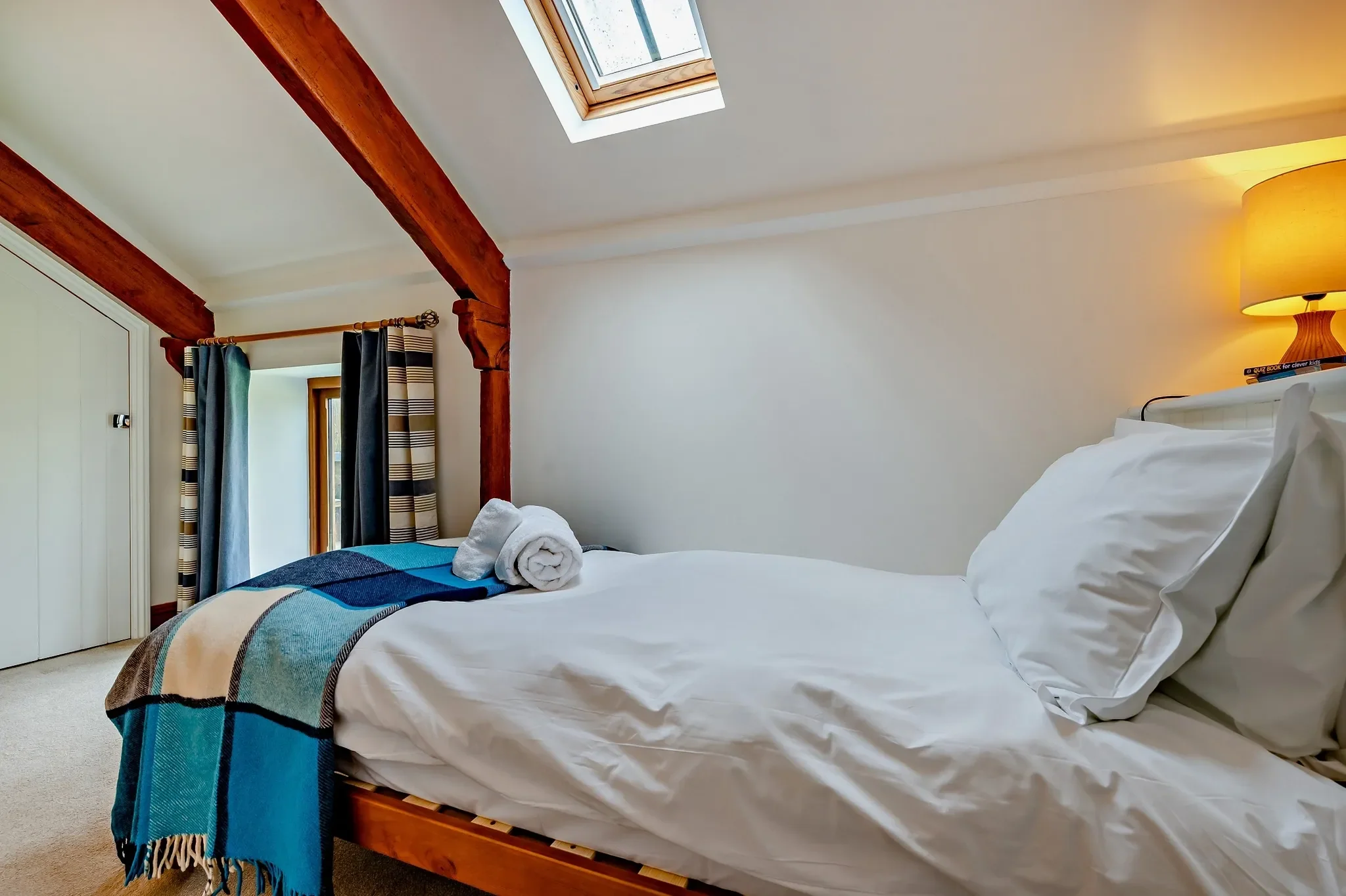 Jack's House single bedroom from the head of the bed, showing the striped curtain, skylight and built-in wardrobe alcove.