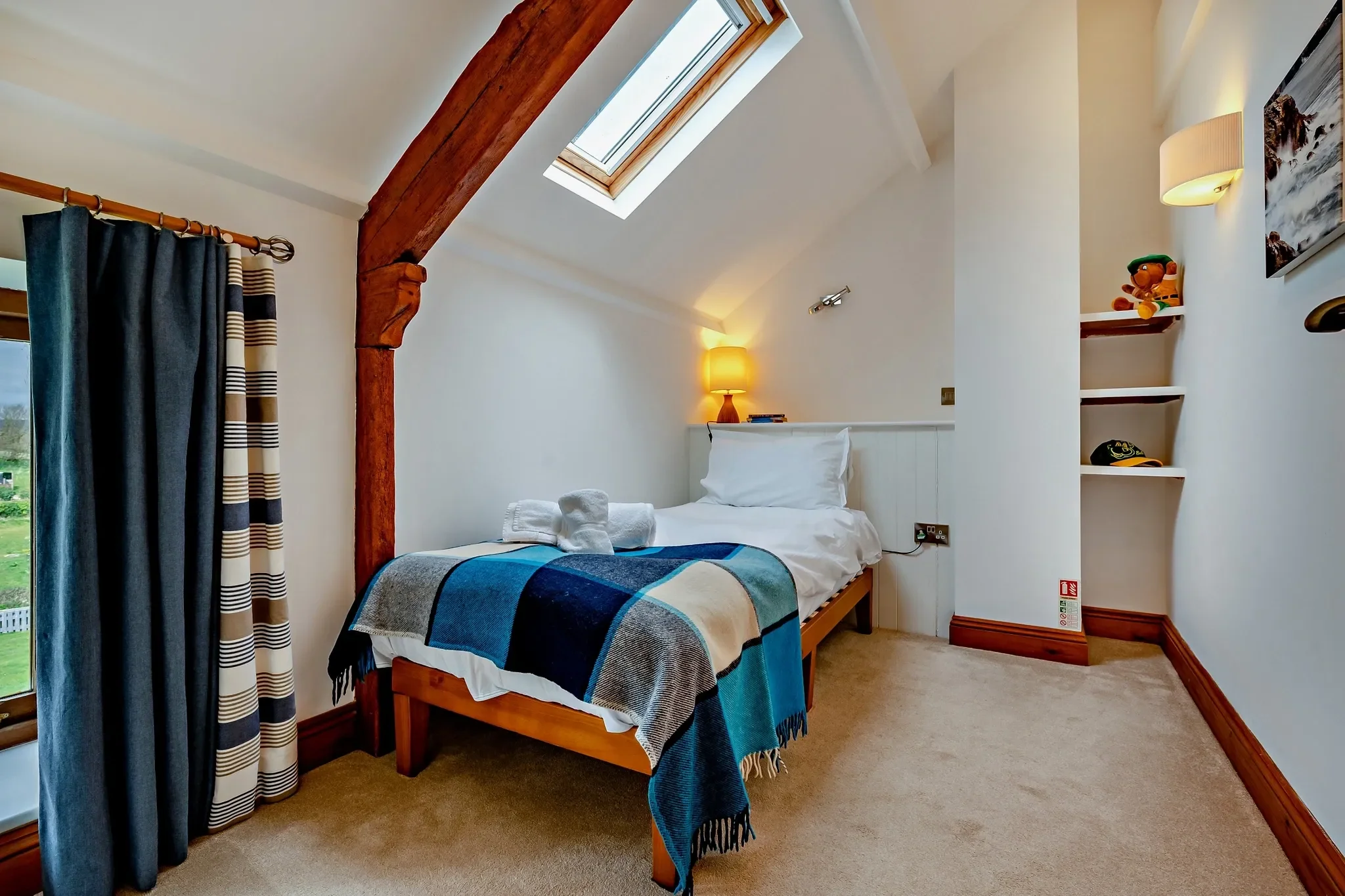 Jack's House single bedroom with skylight, oak-framed bed and open shelving tucked under the eaves.