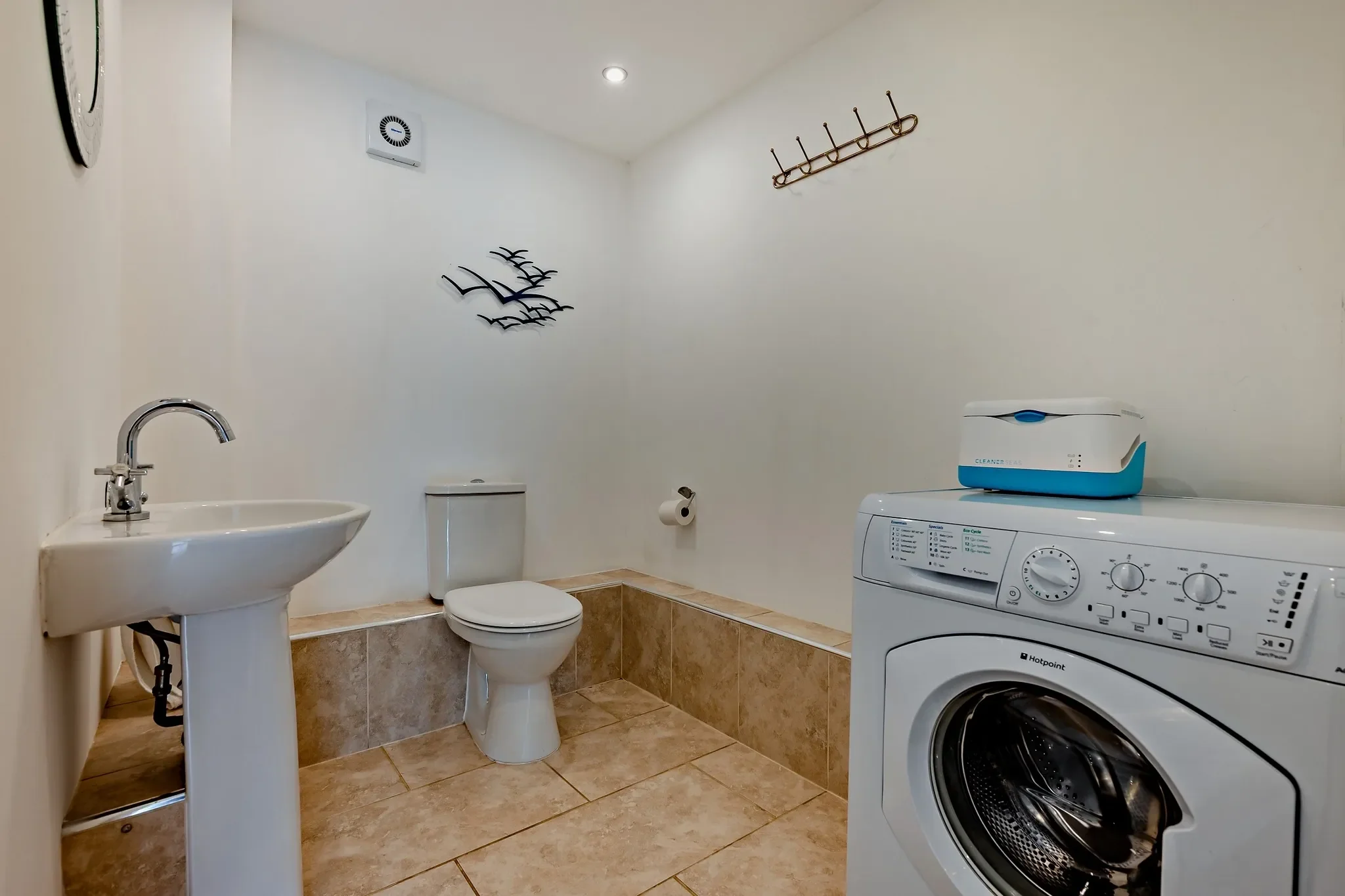 Jack's House ground-floor WC and utility room with pedestal basin, WC and washing machine on tiled flooring.