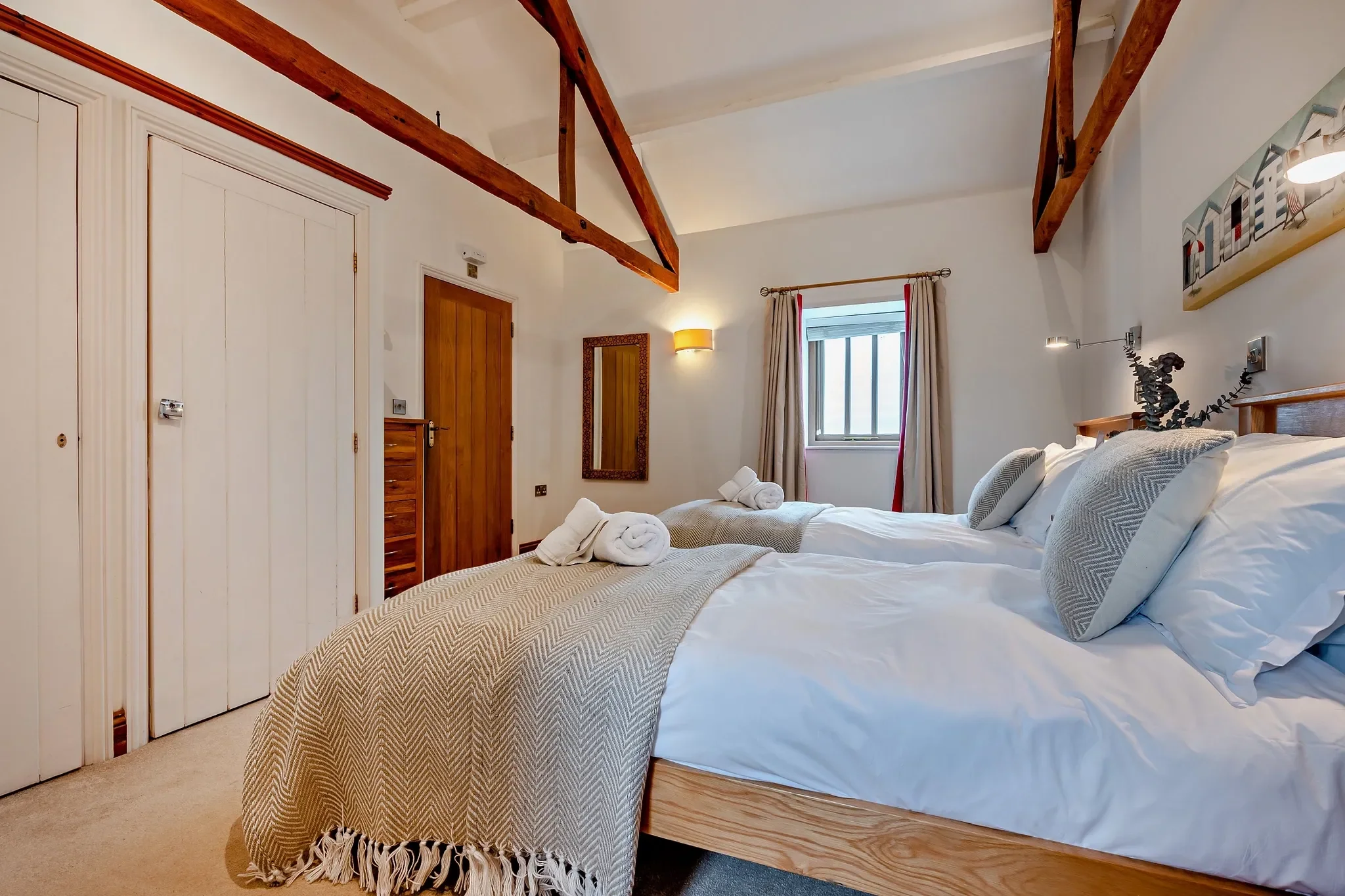 Long Down twin bedroom from the opposite angle showing both single beds, wardrobe alcove and small stone-mullioned window.