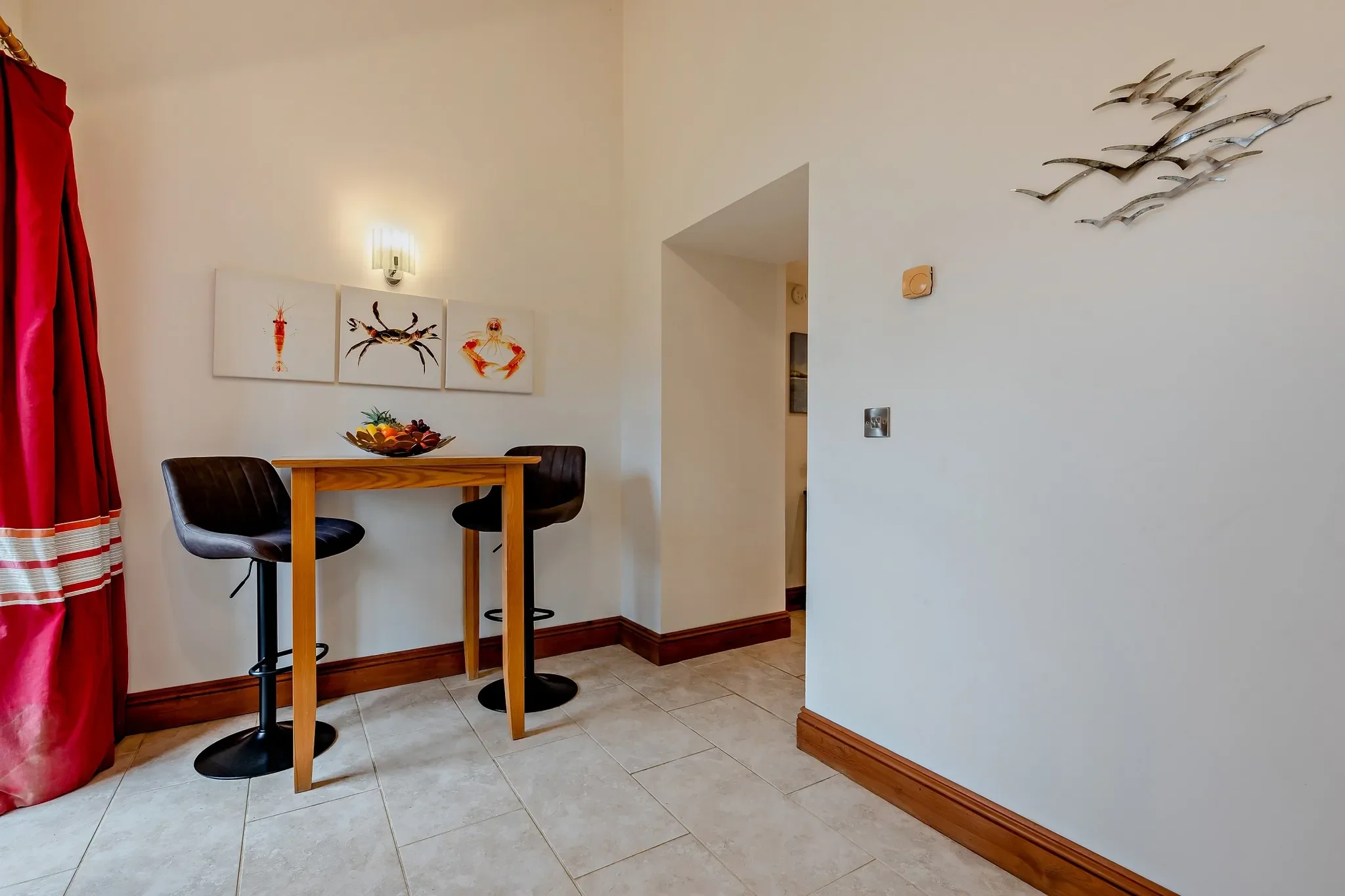 Middle Hill breakfast bar with two leather bar stools, coastal crab and crustacean artwork, and an archway to the lounge.
