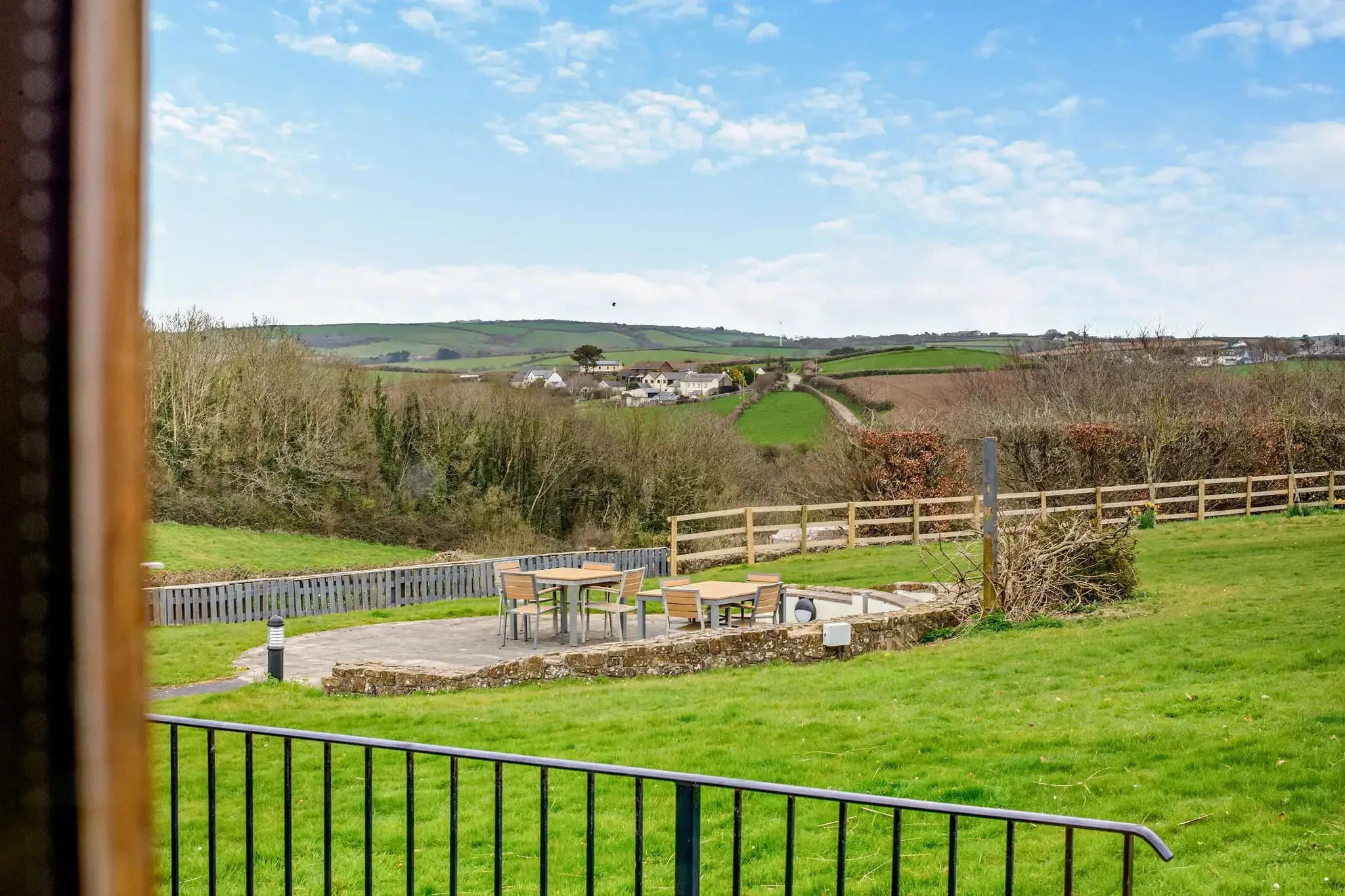 Middle Hill garden and patio terrace with outdoor dining furniture, looking out over the lawns and rolling Cornish countryside.
