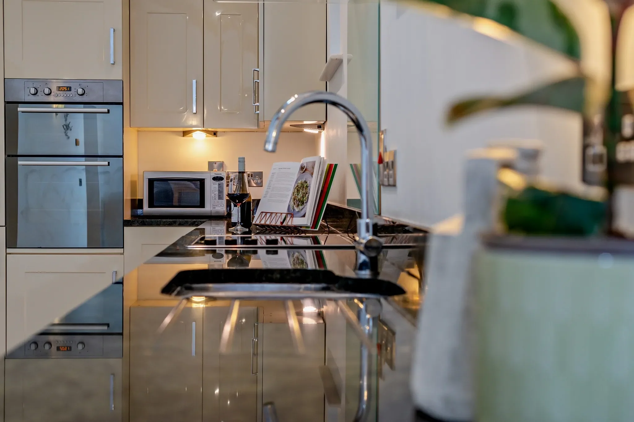 Middle Hill kitchen appliance tower featuring a double oven, microwave, and polished granite sink counter with cookbook stand.
