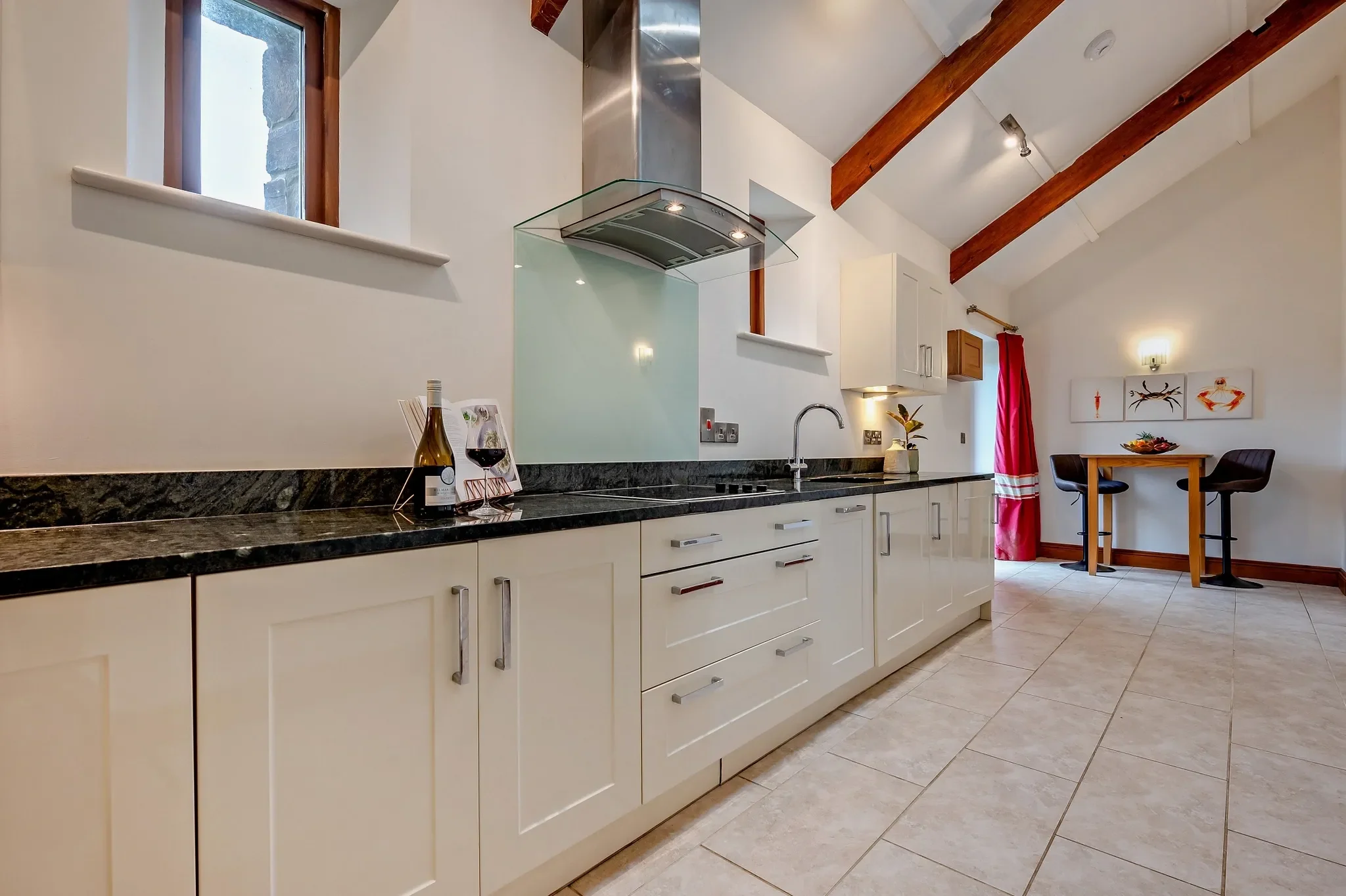 Middle Hill kitchen showing the granite worktop, extractor hood, and a glimpse of the breakfast bar area beyond.