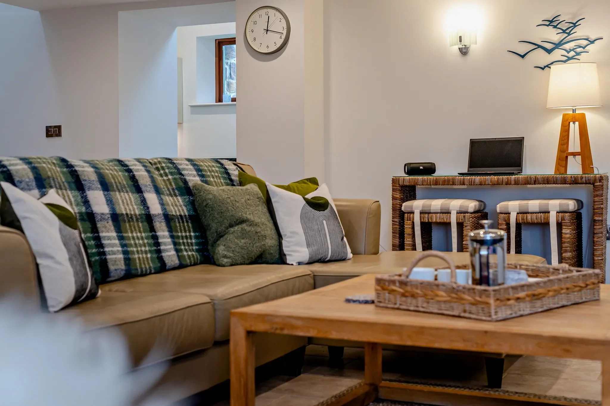 Middle Hill lounge sofa dressed with tartan and green cushions beside a wicker coffee tray and wooden side table.