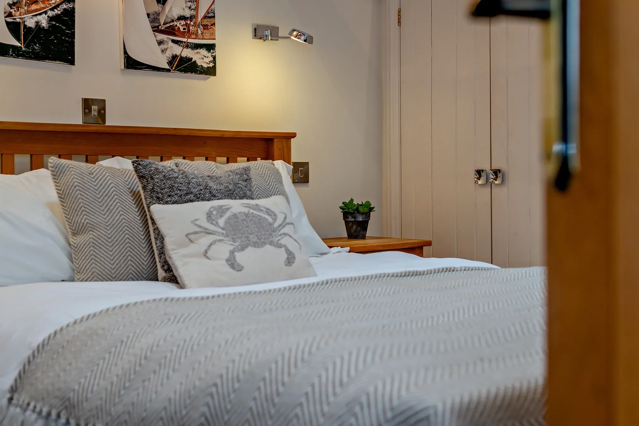 Middle Hill master bedroom close-up of the king bed dressed with a herringbone throw and crab-motif cushion.