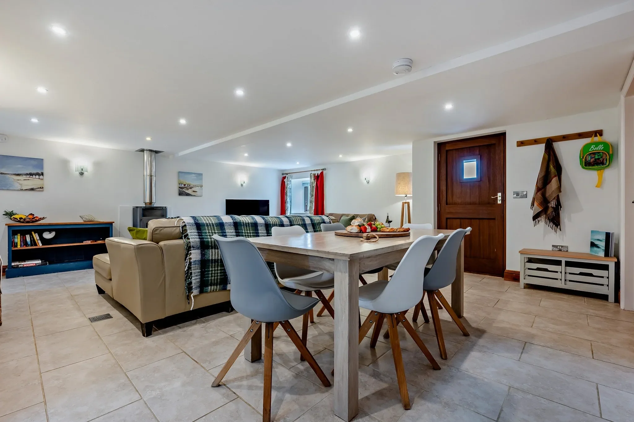 Middle Hill open-plan ground floor showing the dining table and chairs flowing into the lounge with log burner beyond.