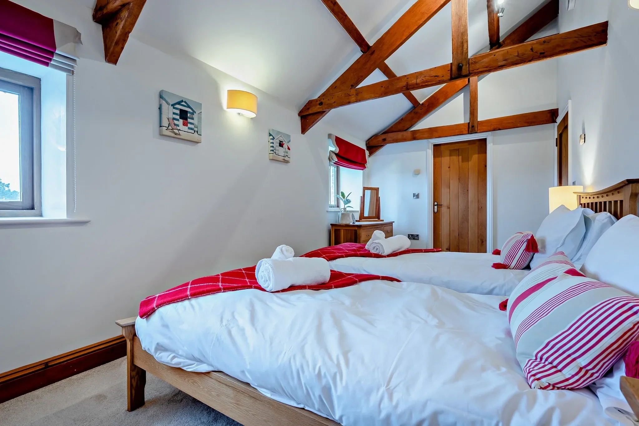 Middle Hill twin bedroom from the window end showing both beds, nautical artwork, and a dressing mirror in the corner.
