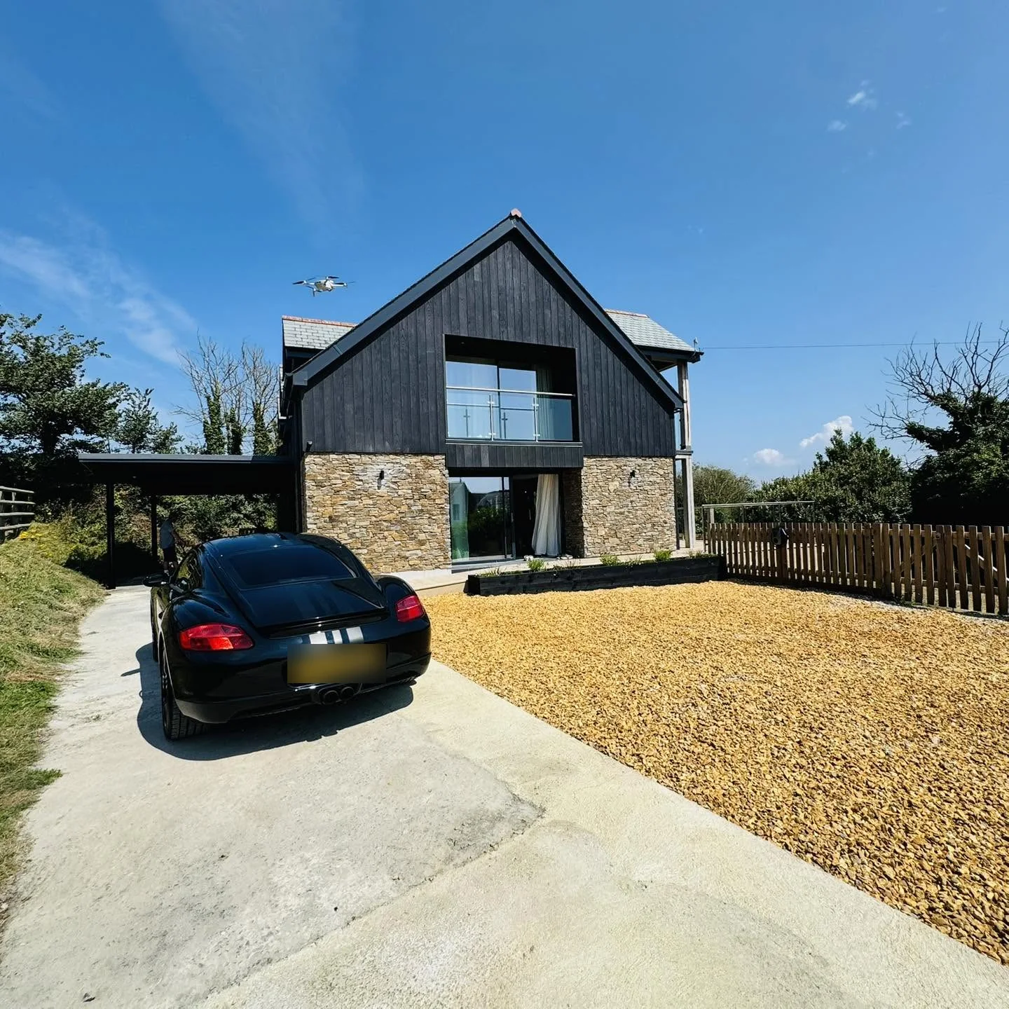 The front of Nan's House, with its carport, gravel parking area and stone-and-timber frontage