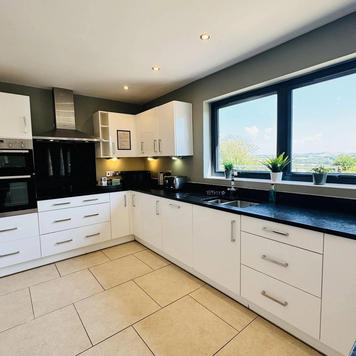 The kitchen at Nan's House, with gloss units, granite worktops, a double oven and countryside views from the window