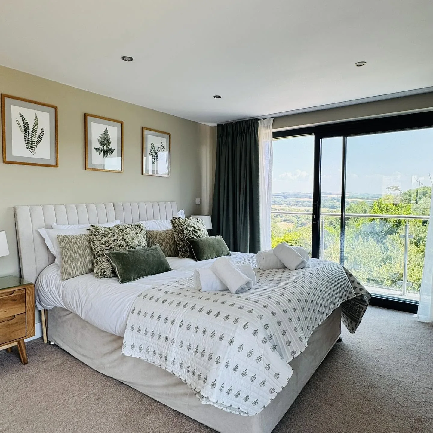 A bedroom at Nan's House with glass doors opening onto a balcony above the Cornish fields