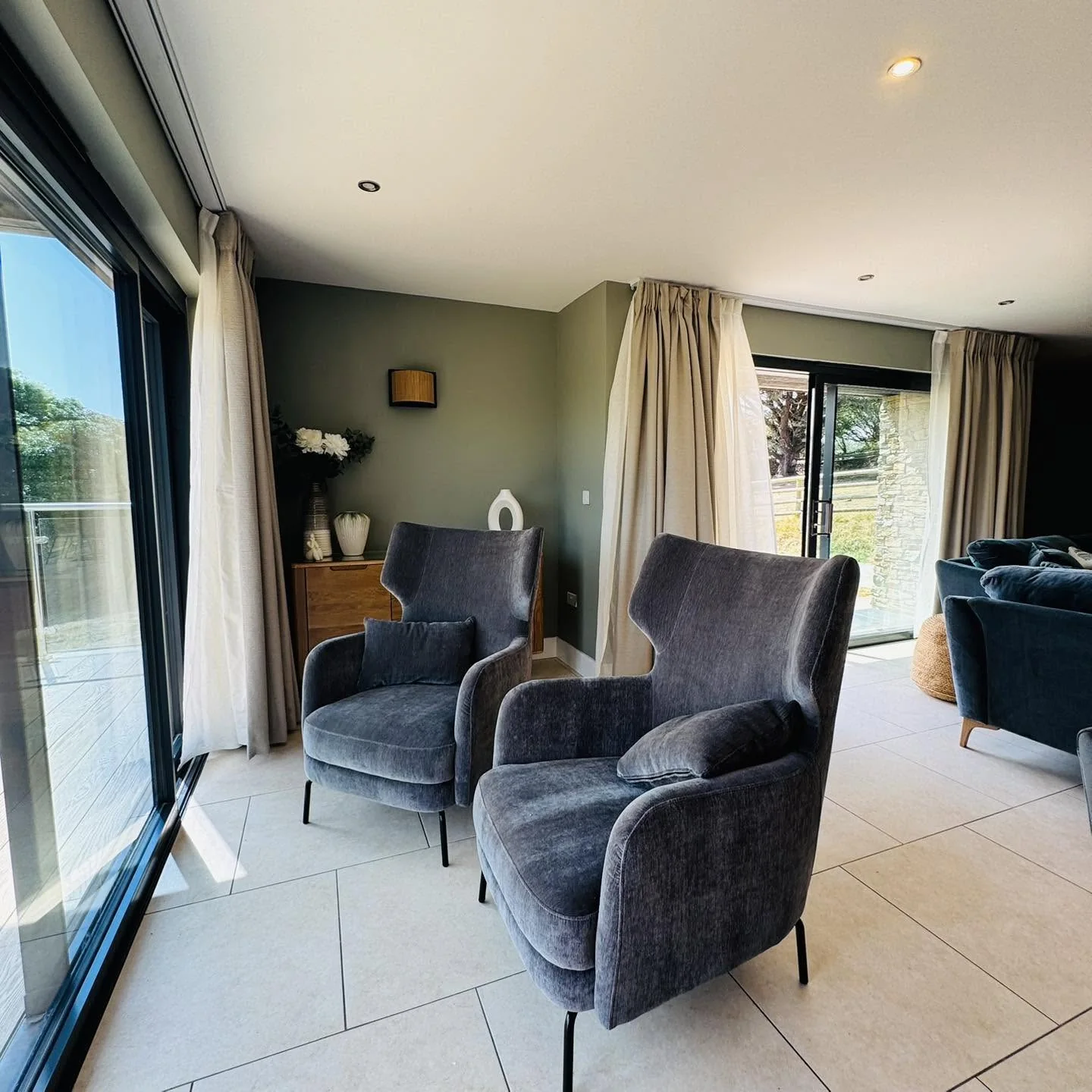 A quiet sitting corner at Nan's House with two wingback armchairs beside full-height garden doors