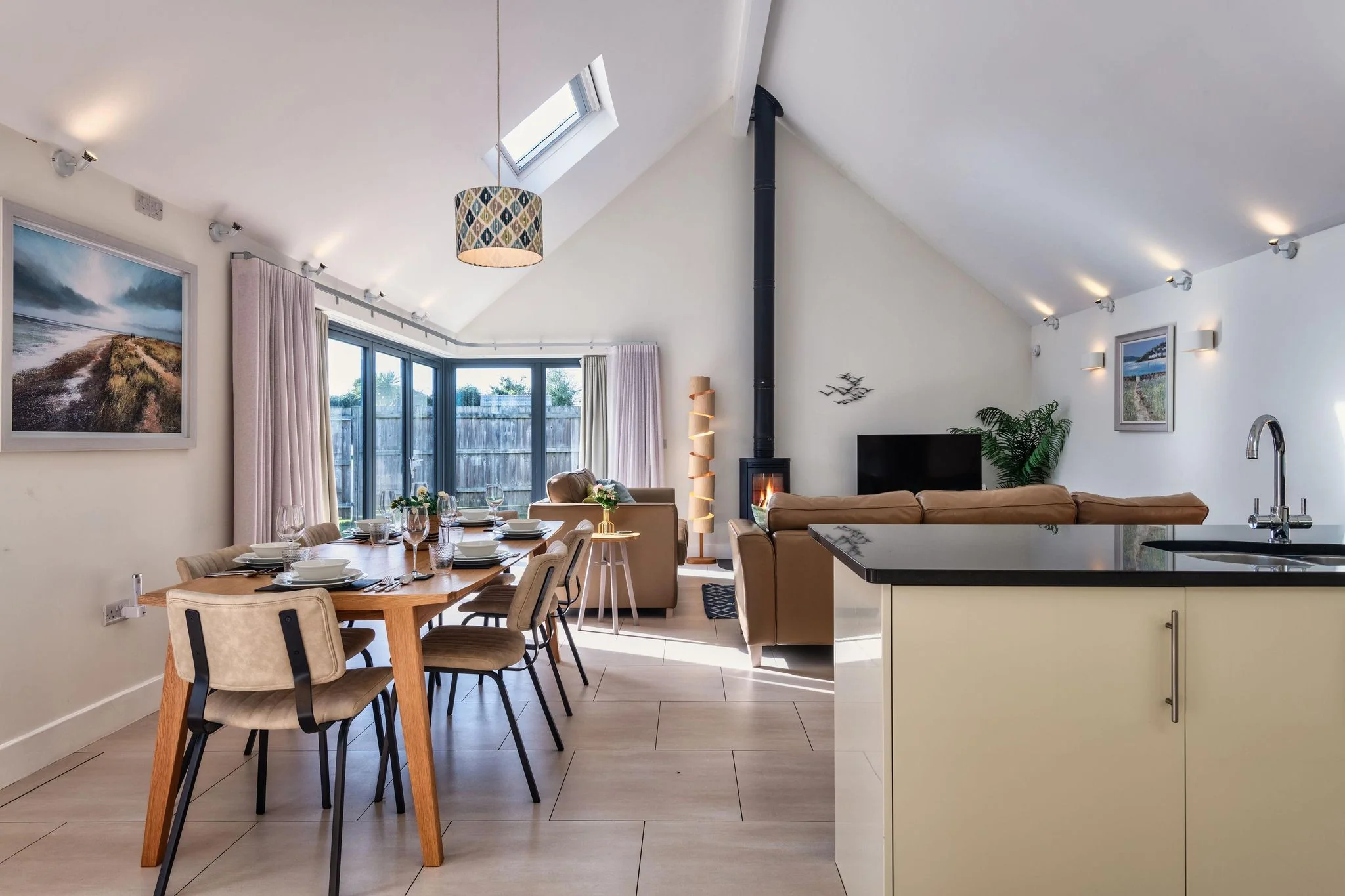 Nettlecoombe master bedroom with king-size bed, garden-view sliding doors and coastal artwork above the headboard.