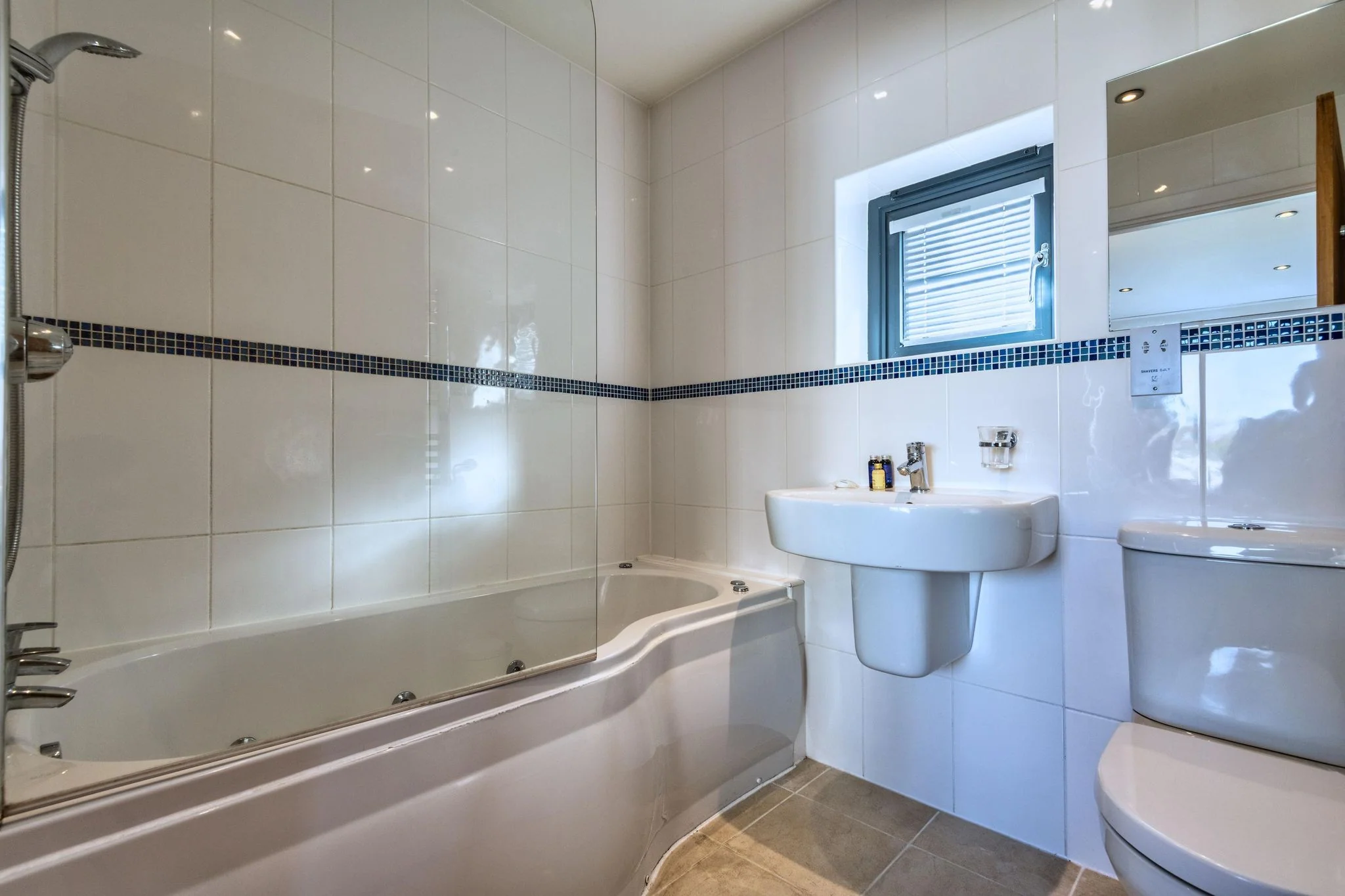 Nettlecoombe second double bedroom with a navy-headboard king-size bed, striped throw and garden-facing doors.