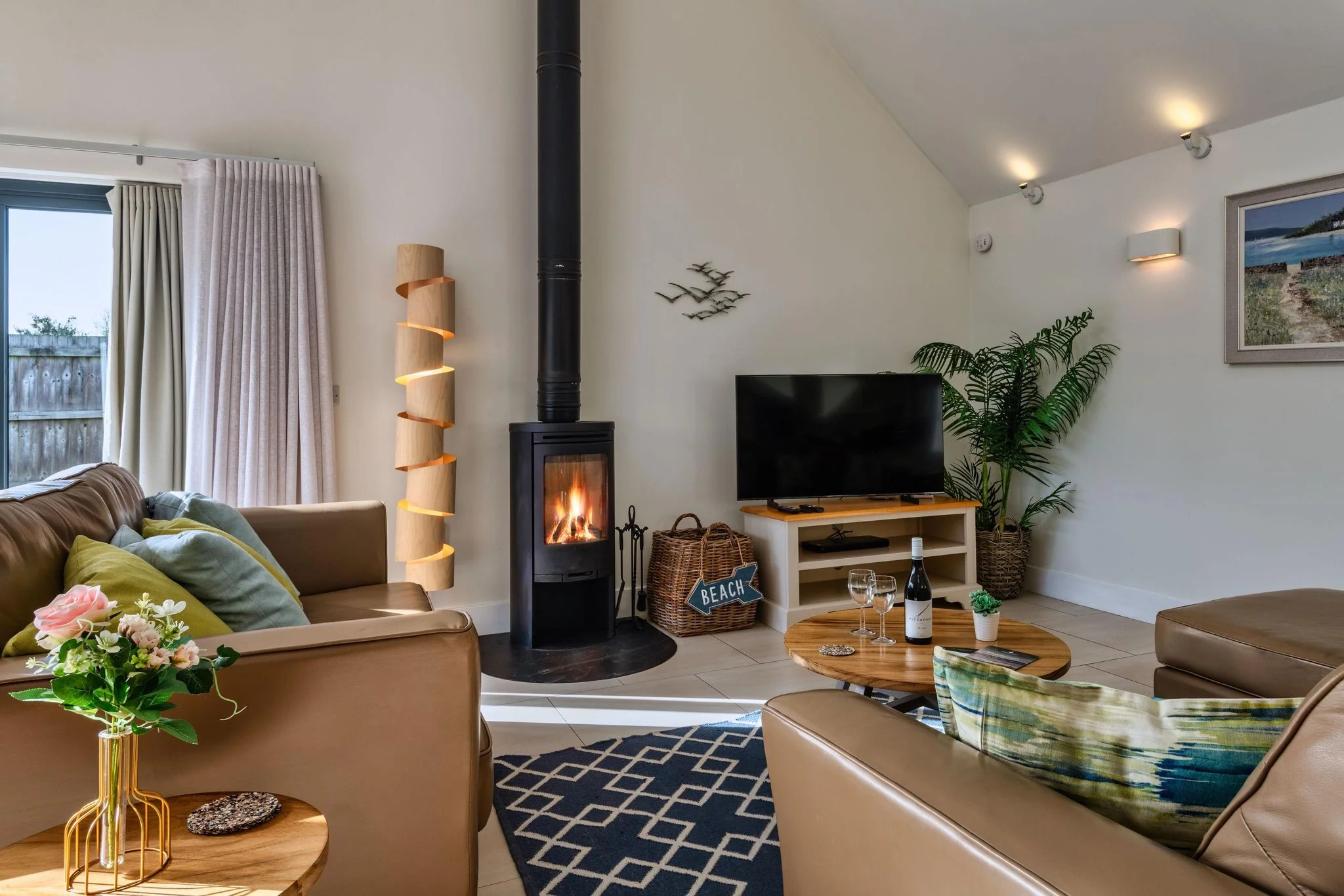 Nettlecoombe sitting area featuring a glowing wood-burning stove, leather seating and vaulted ceiling.