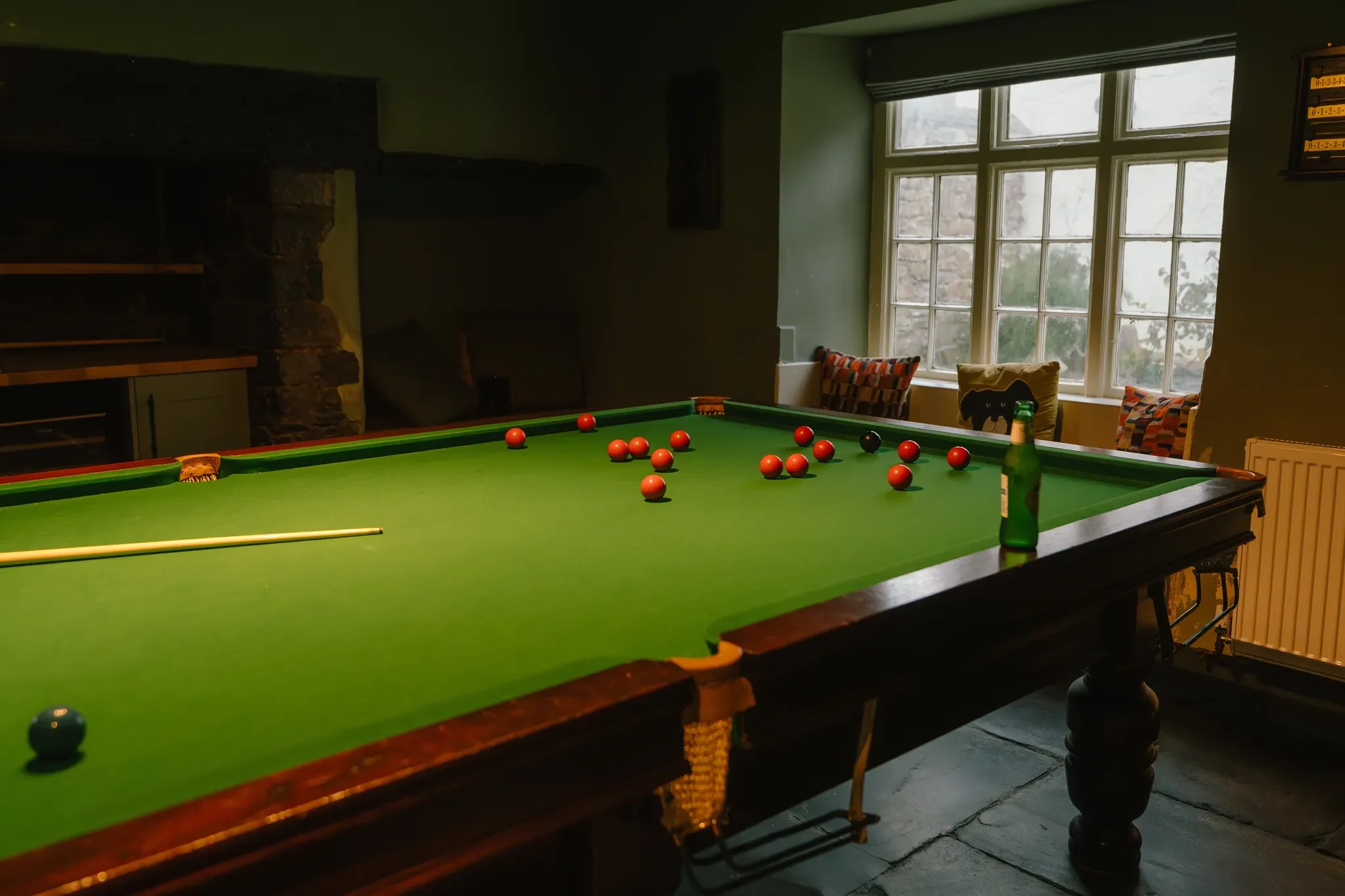 The Farmhouse games room with a full-size snooker table set on slate flagstones within original stone walls.