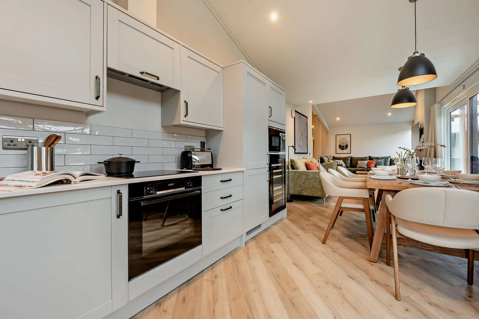 Trelowen lodge kitchen with shaker units, integrated appliances and the living space beyond