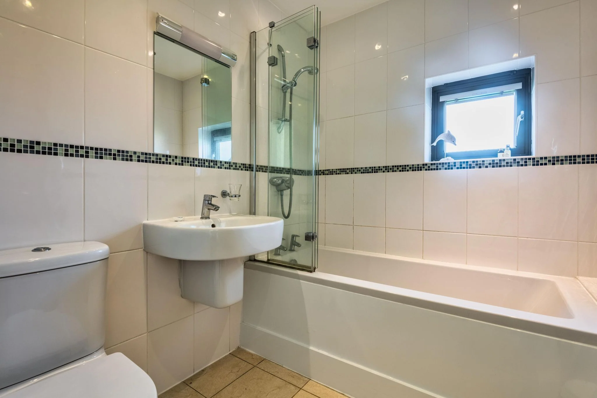 Trevelyan family bathroom with full-size bath, overhead shower, pedestal basin and mosaic tile border.