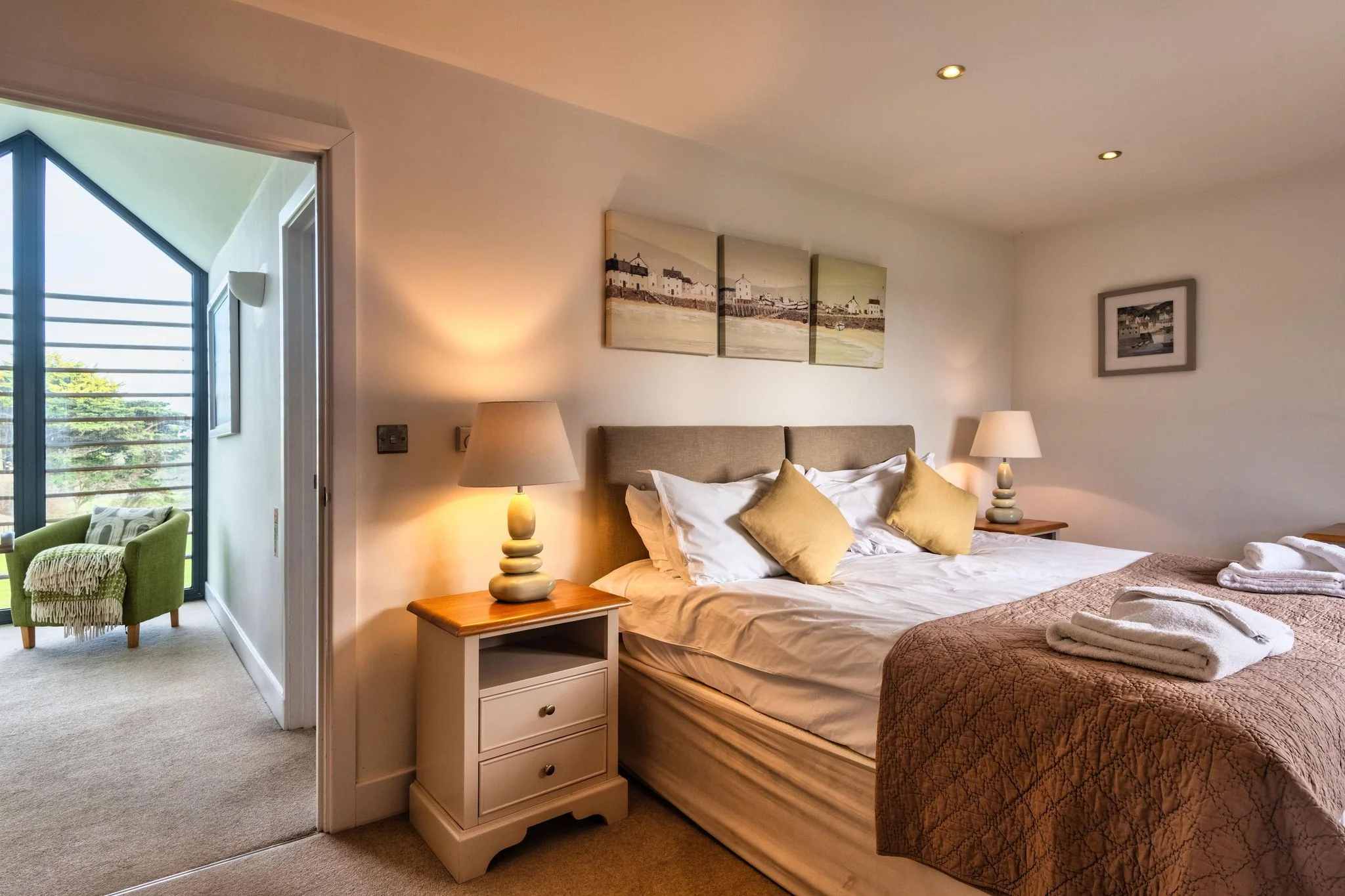 Trevelyan master bedroom with king-size bed, warm bedside lamps and doors to a private balcony with open views.