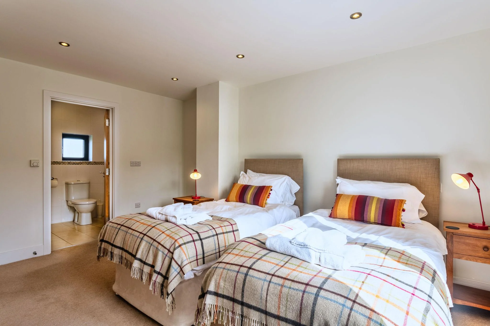 Venners twin bedroom from the far end showing both beds with plaid throws and the en-suite doorway beyond.