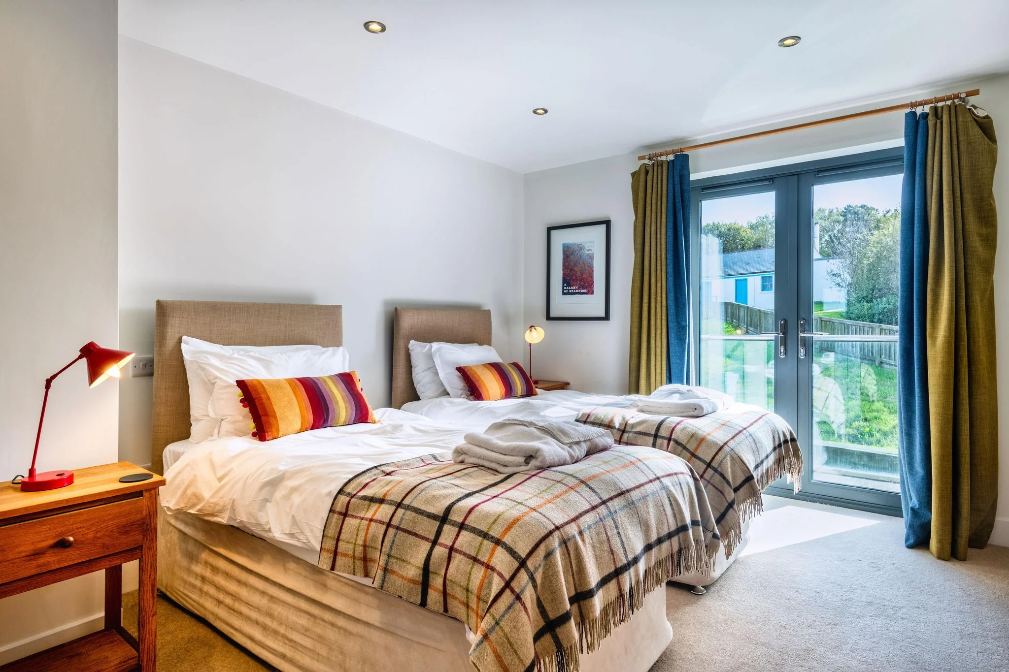 Venners twin bedroom with two single beds dressed in tartan throws and French doors to the garden.