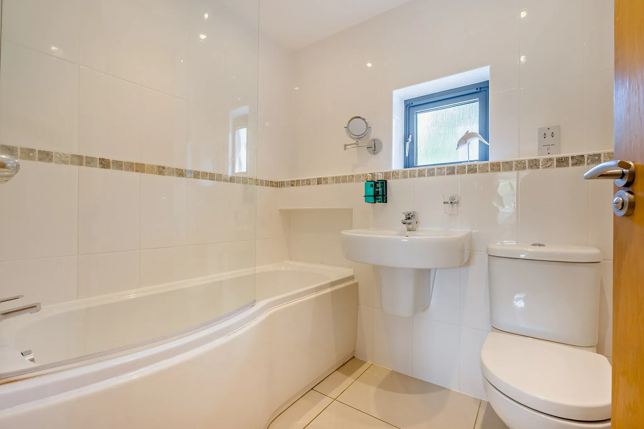 Warrens family bathroom with full-size bath, mosaic tile border, pedestal basin and frosted window.