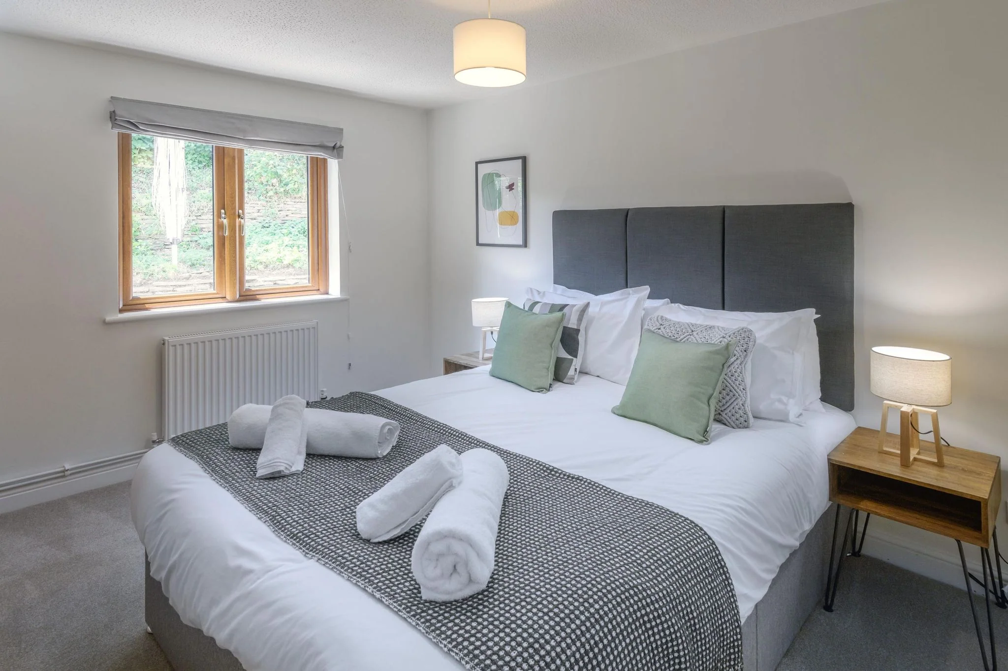 Windy Hills double bedroom with dark upholstered headboard, green accent cushions, and a garden-facing window.