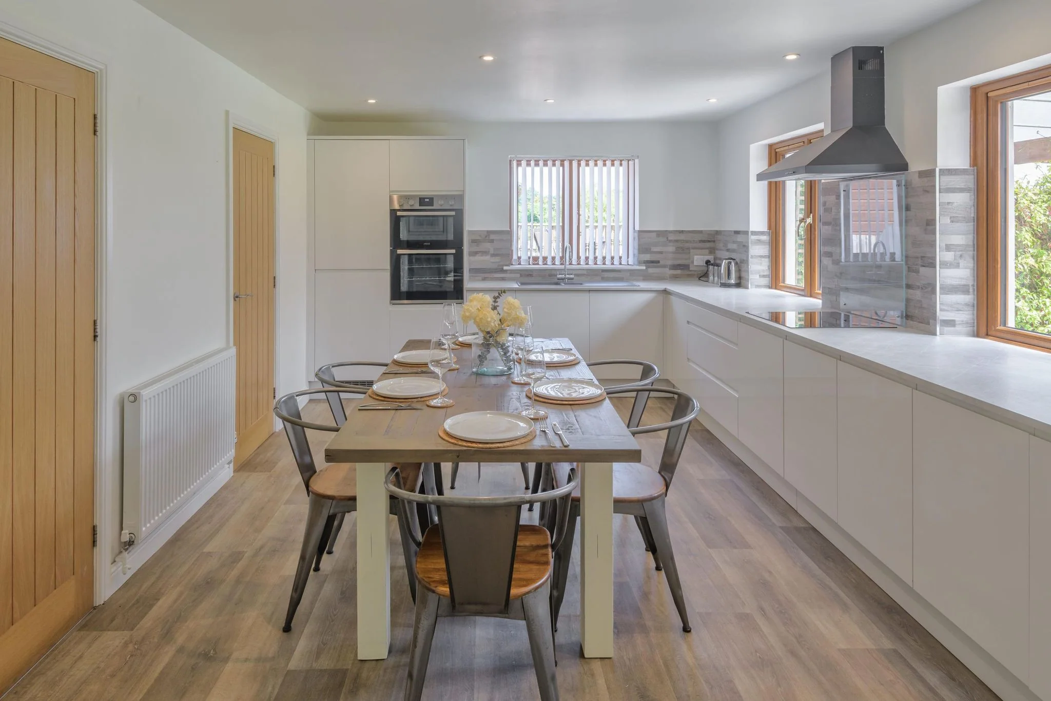 Windy Hills open-plan kitchen and dining area with a six-seat table, white fitted units, double oven, and range hood.