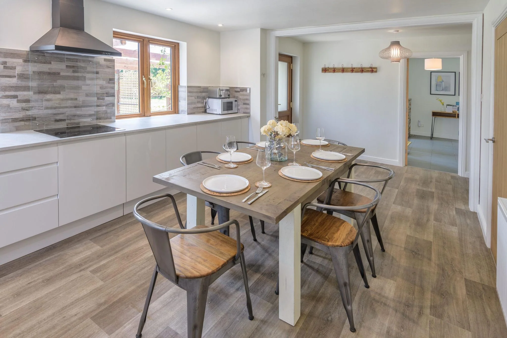 Windy Hills kitchen and dining table viewed from the far end, looking through to the entrance hallway beyond.