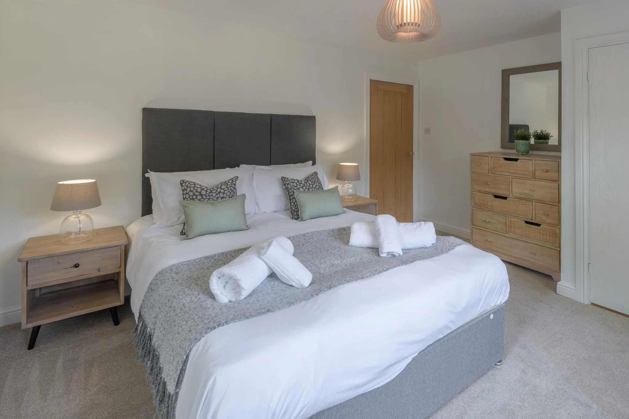 Windy Hills master bedroom with king-size bed, matching bedside tables with lamps, and a light wood chest of drawers.