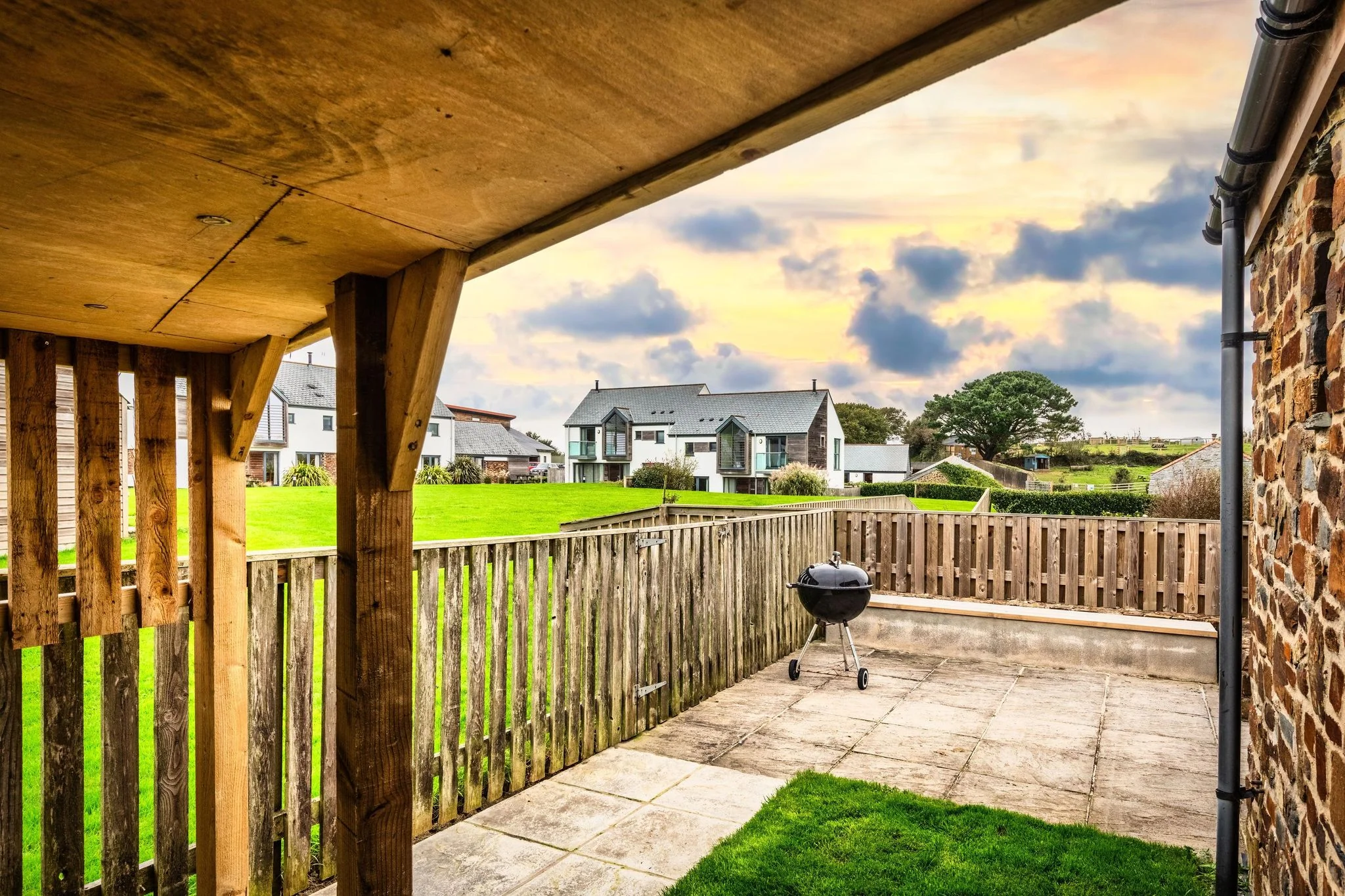 Woody Platt rear garden and patio viewed from the covered pergola, with BBQ and open countryside beyond the fence.