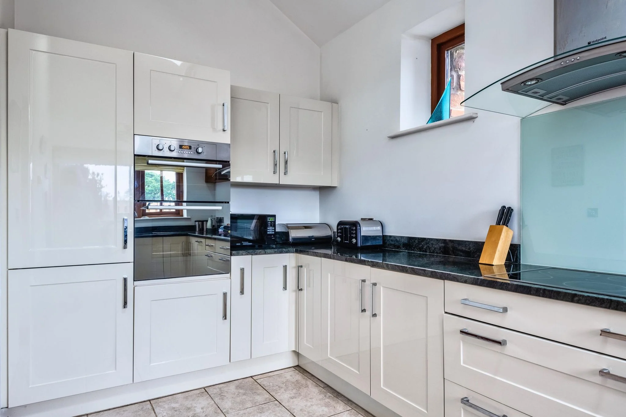Woody Platt kitchen showing full-height integrated oven, microwave, toaster and generous granite worktop space.
