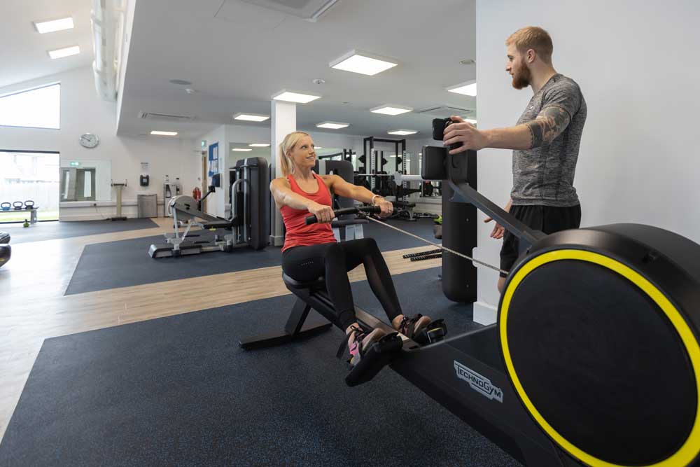 Personal trainer coaching a member on a rowing machine during a wellness consultation at The W Club, Whalesborough, Bude Cornwall