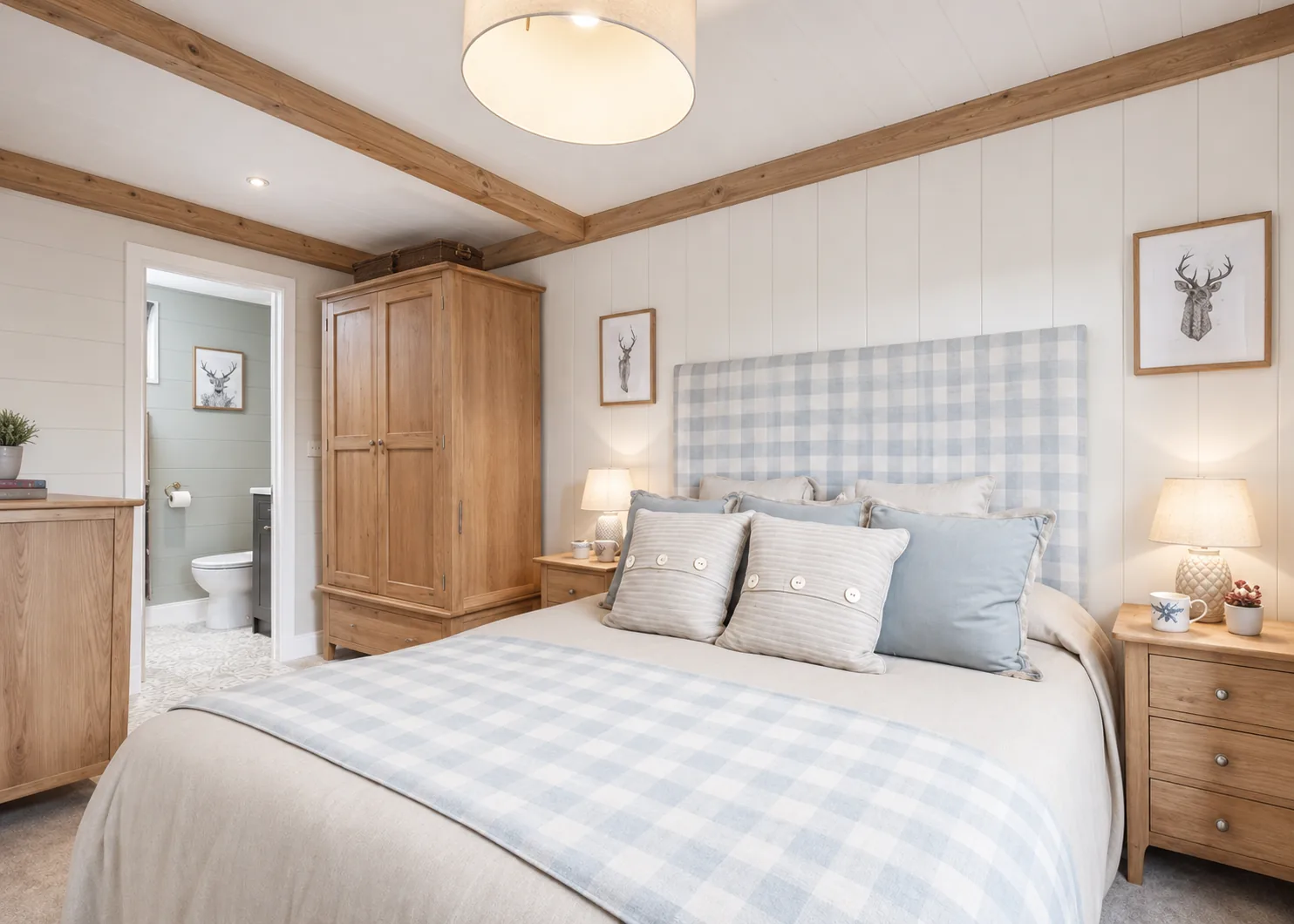 Double bedroom in the two-bedroom Gwithva lodge, with a checked headboard and en-suite beyond