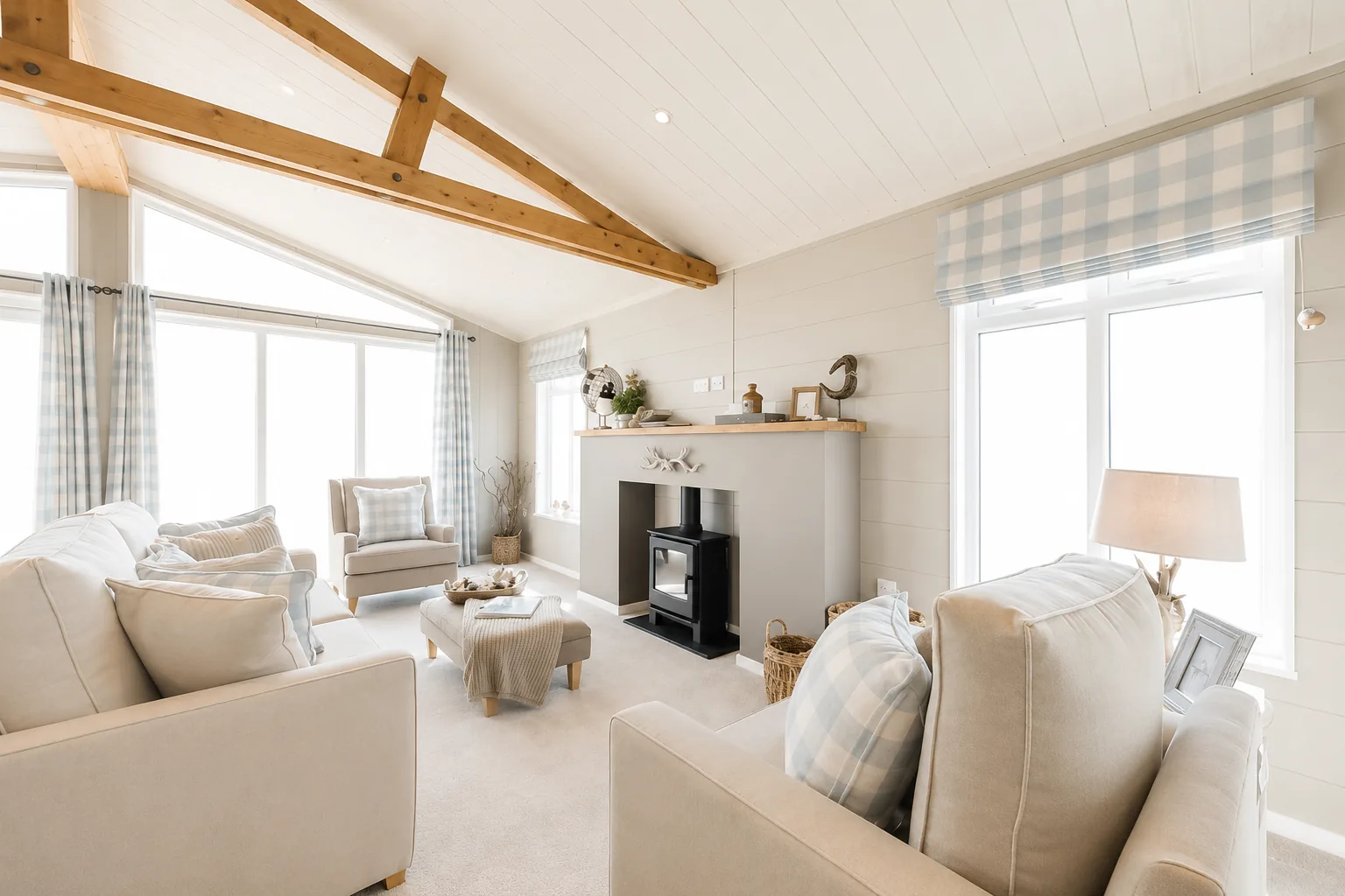 Living room of the two-bedroom Gwithva lodge, with a vaulted timber ceiling, exposed beams and the feature fireplace