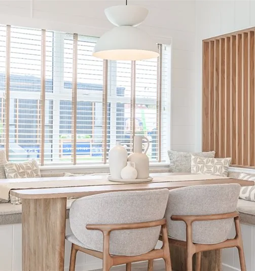 Dining area of the three-bedroom Gwithva Prestige Skylark, with banquette seating and a slatted timber screen