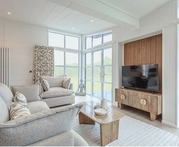 Living room of the three-bedroom Gwithva Prestige Skylark, with a walnut media wall and full-height windows