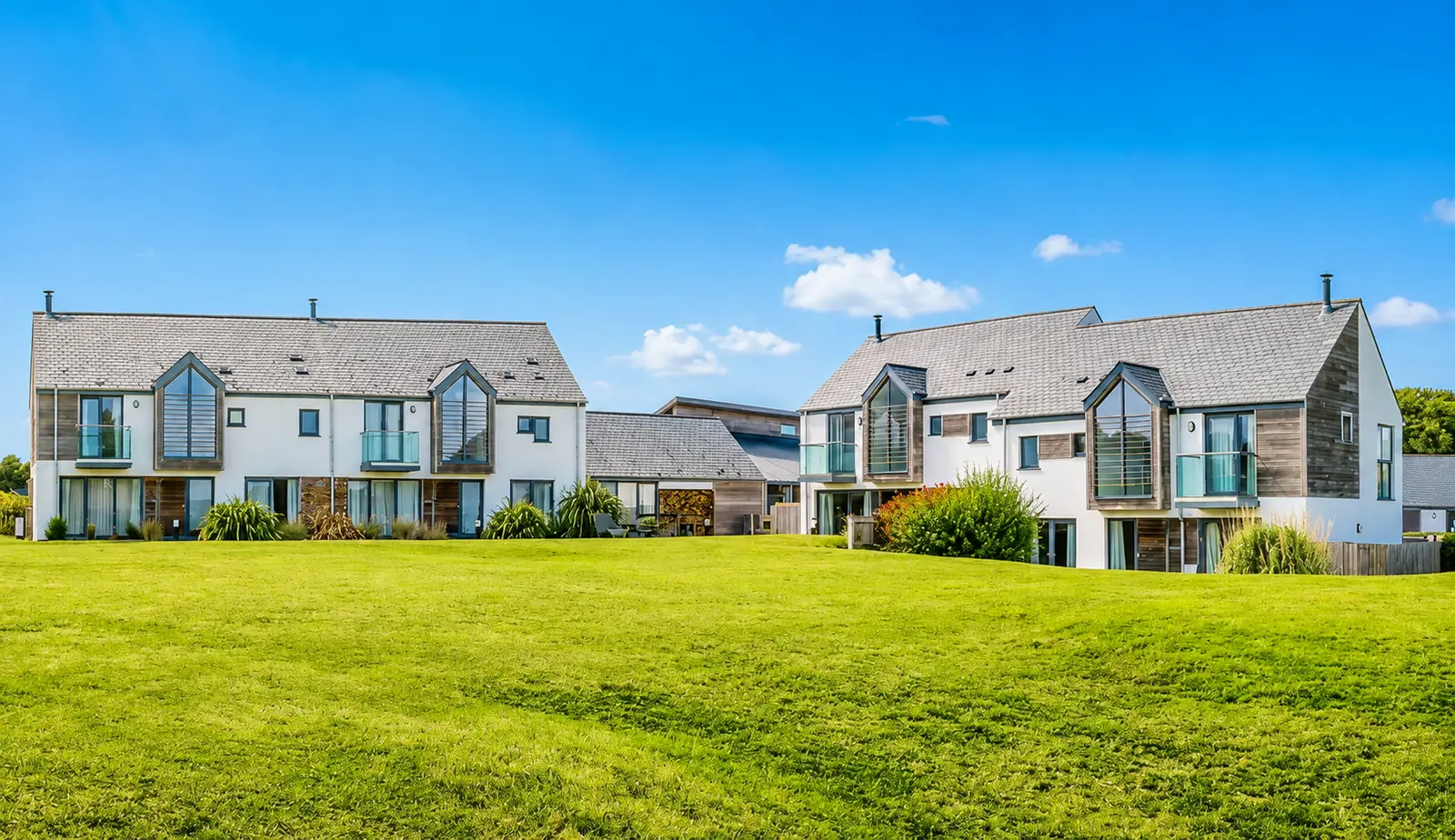 Holiday homes for sale at Whalesborough Farm Resort, Cornwall — overlooking the estate lawn under blue skies