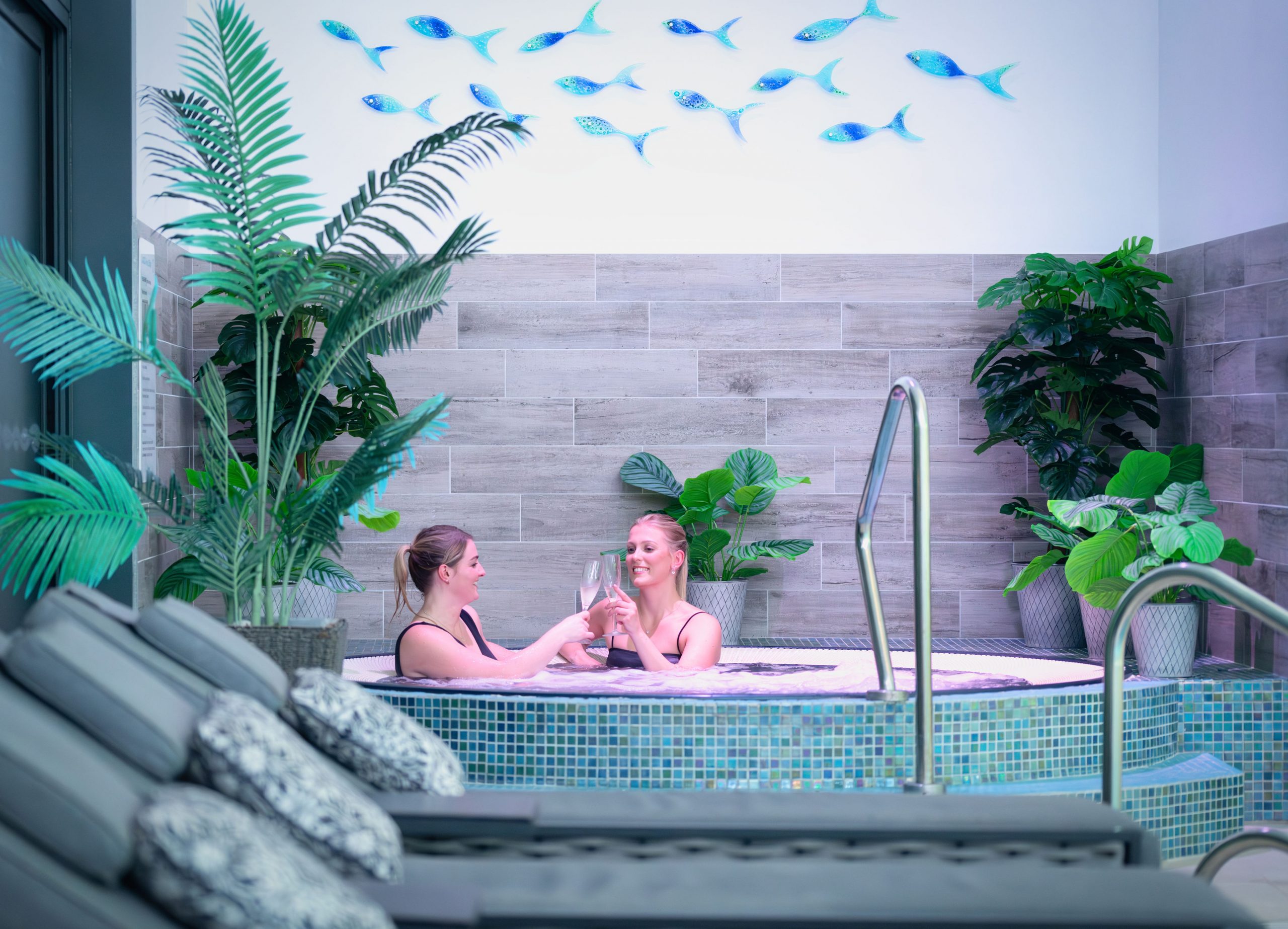 Blue-lit indoor relaxation pool with loungers at The W Club, Whalesborough, Bude, Cornwall